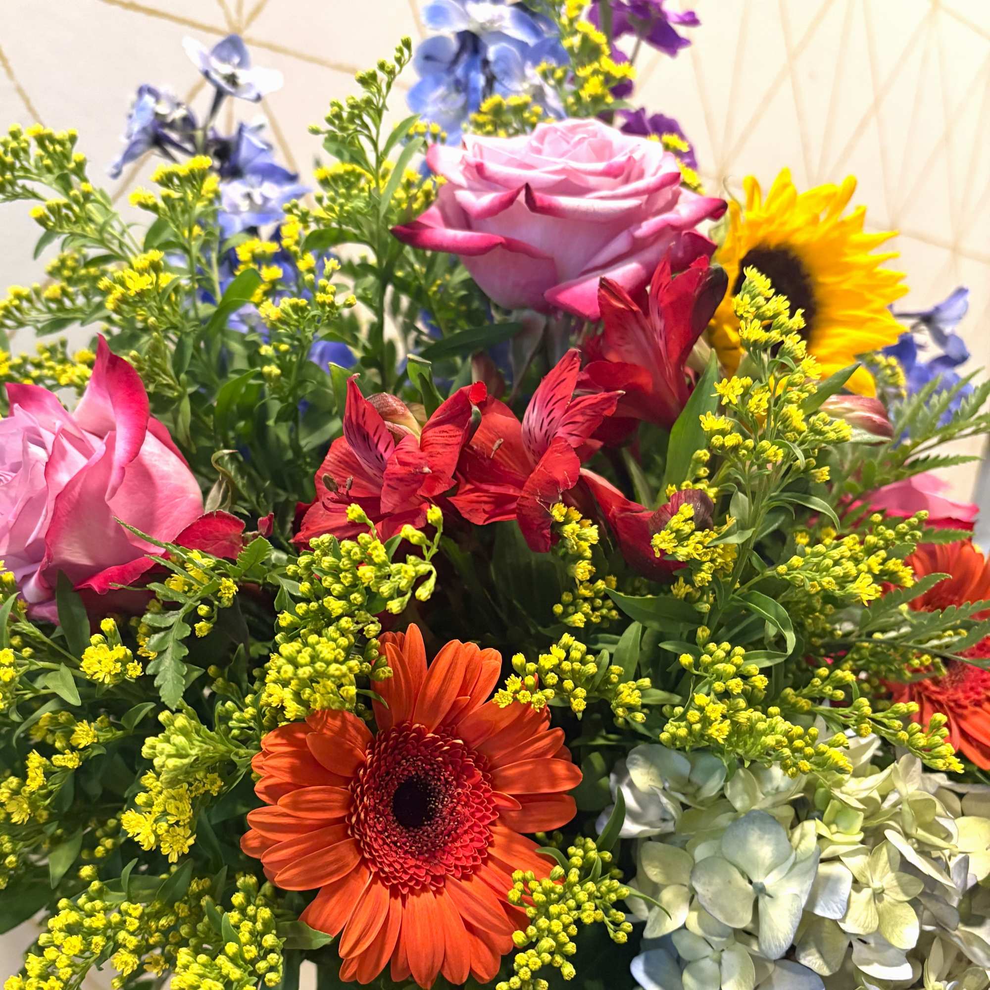 Mixed bouquet with roses, gerbera daisies, sunflowers, and blue flowers