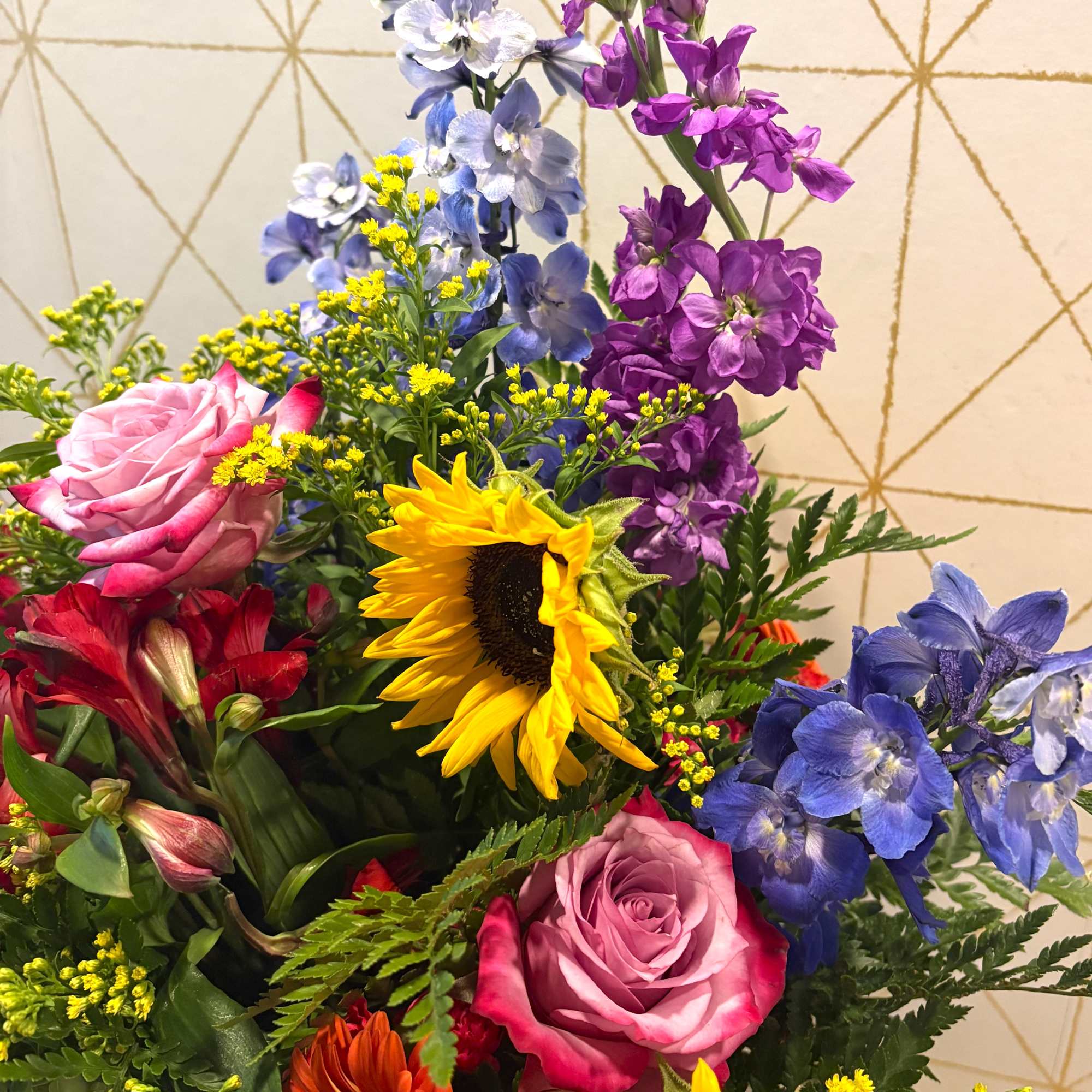 Mixed bouquet with roses, sunflowers, and blue and purple flowers