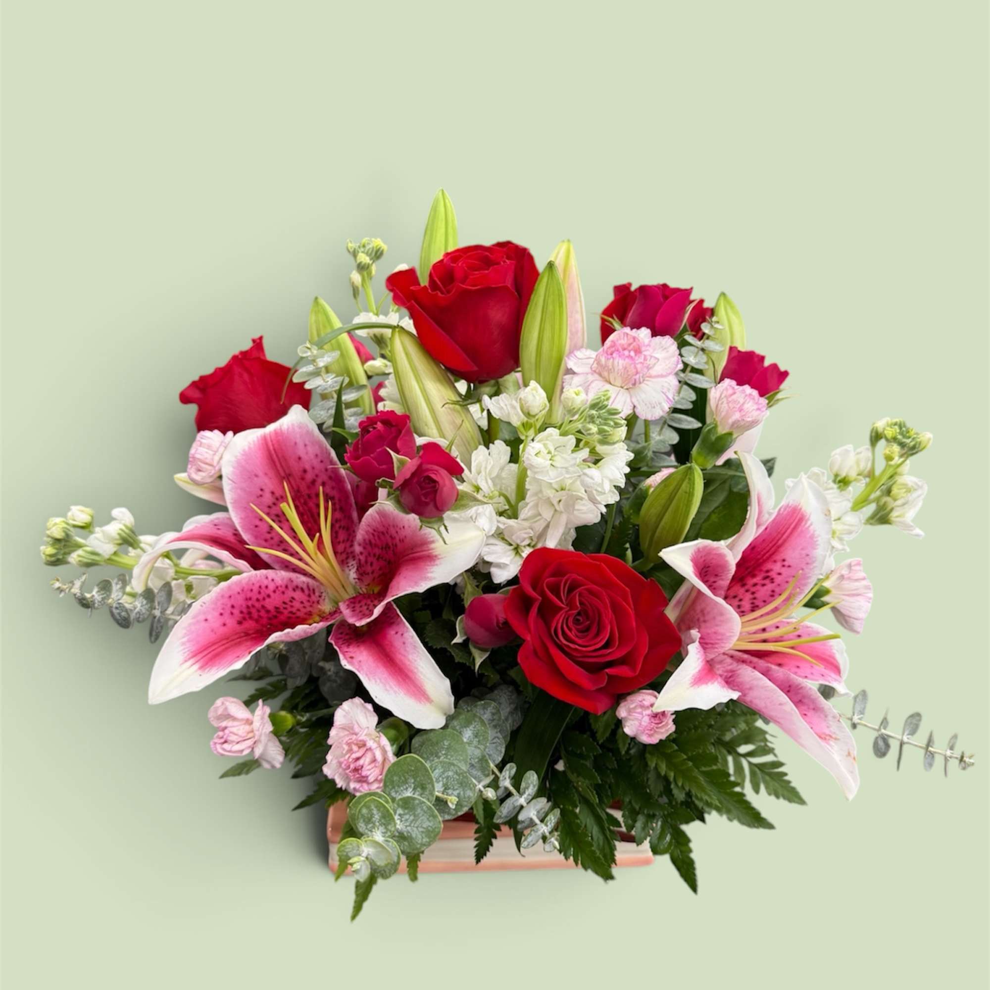 Bouquet of red roses and pink lilies in a low rectangular container