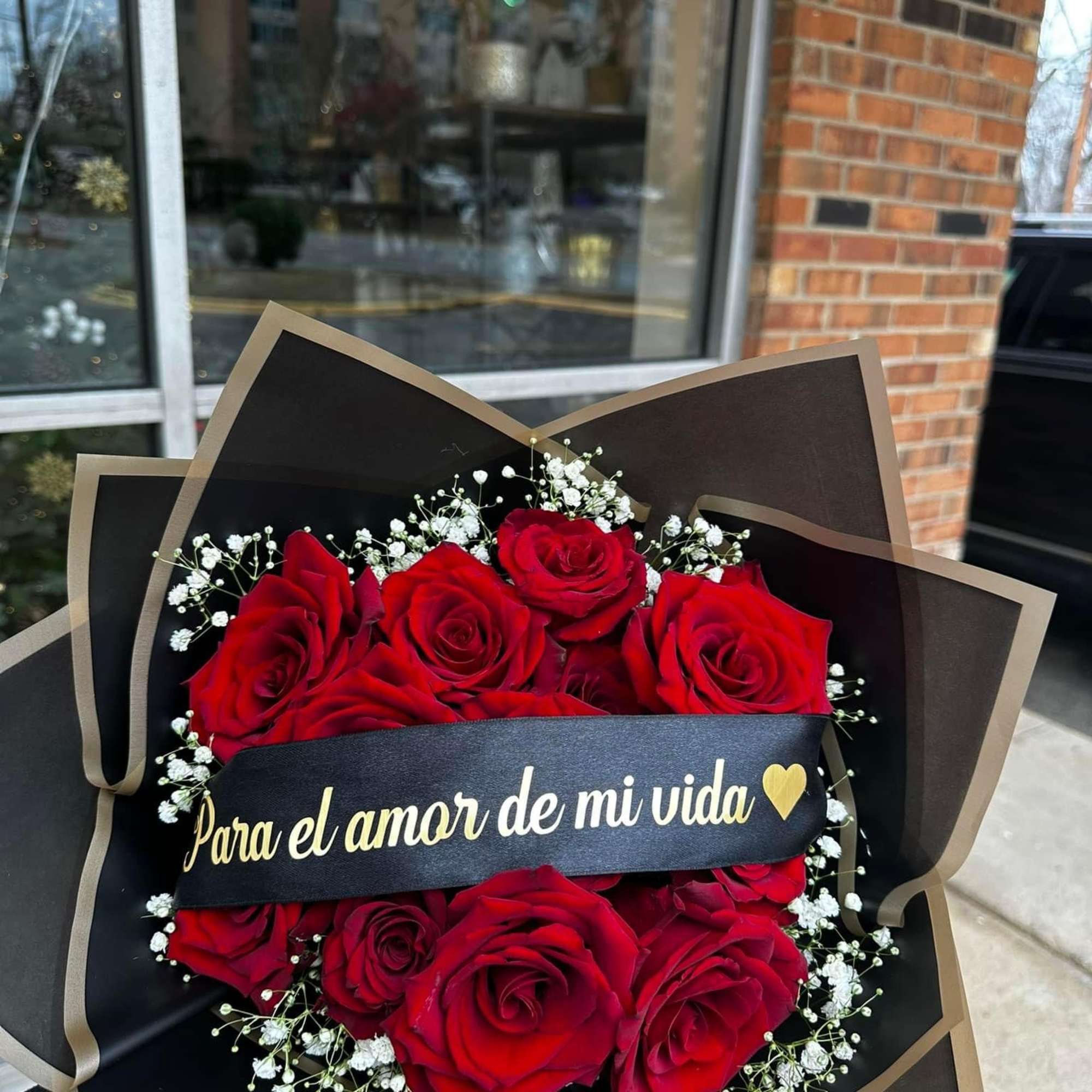 Bouquet of red roses with baby's breath and a black ribbon banner