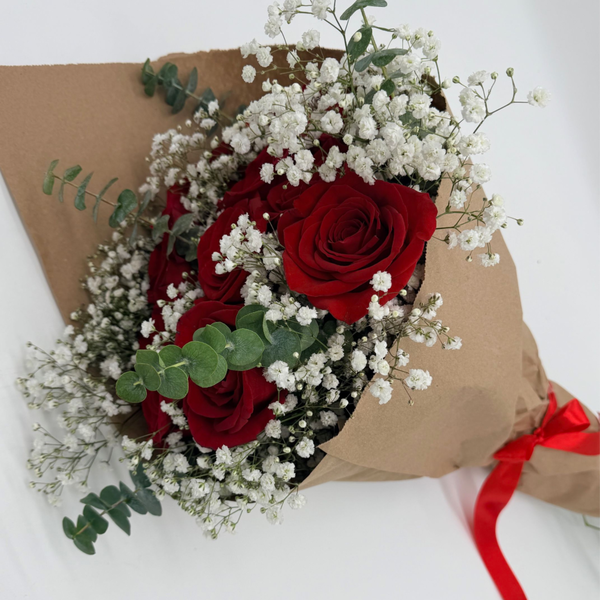Bouquet of red roses and white baby's breath wrapped in brown paper
