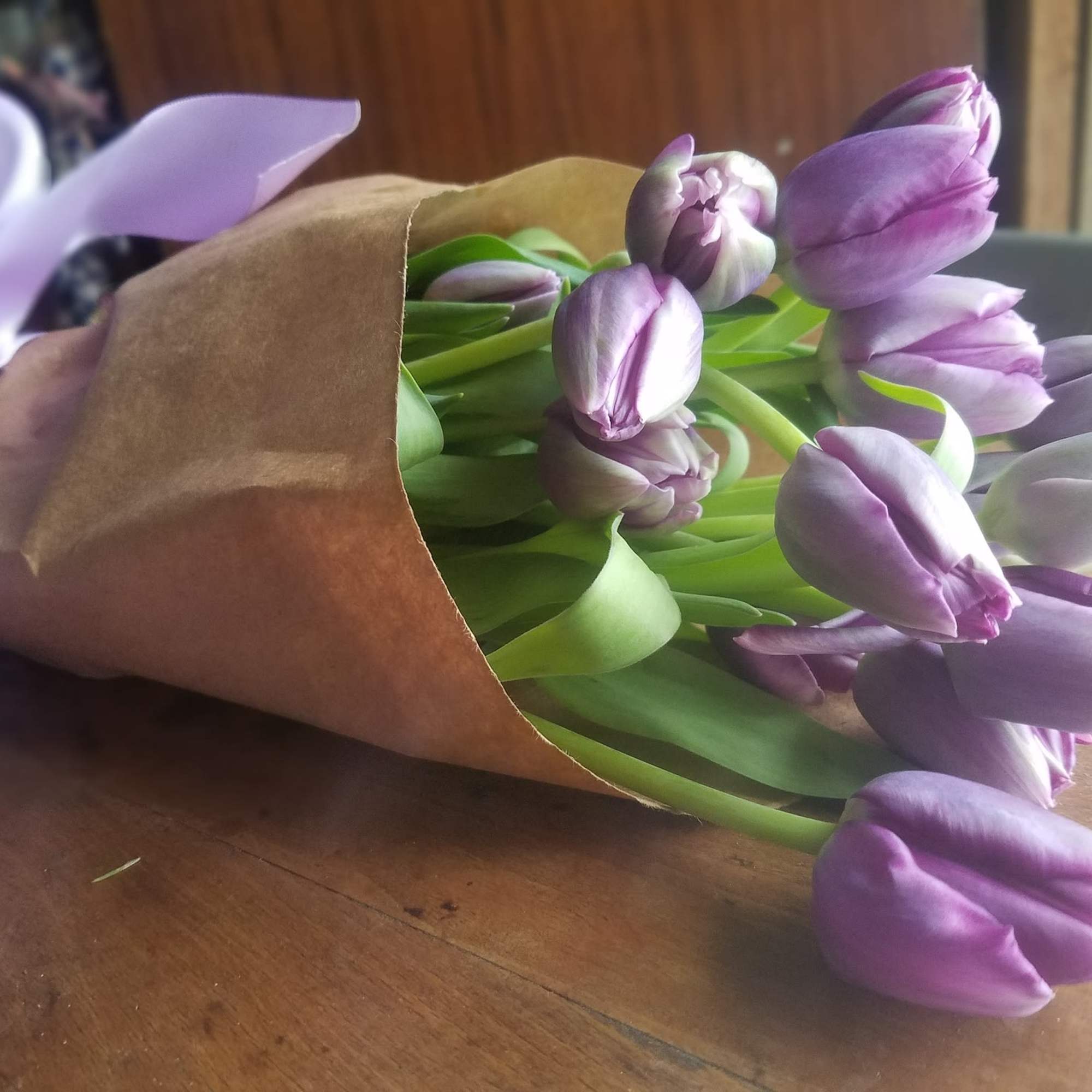 Bouquet of purple tulips wrapped in brown paper with a lavender ribbon