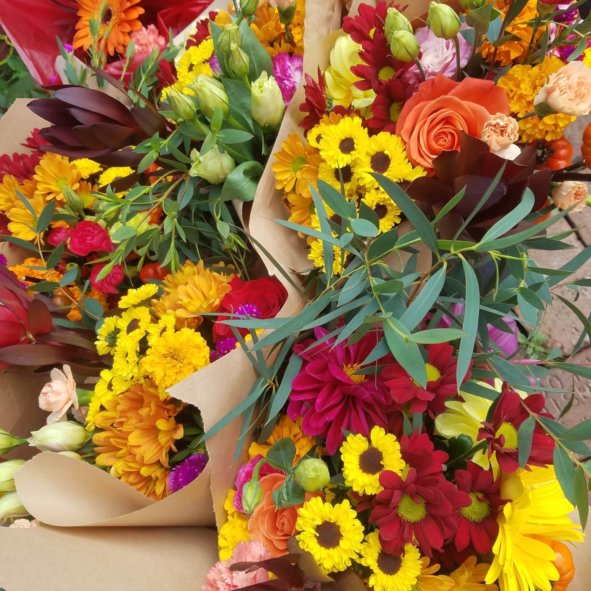 Assorted colorful flower bouquets wrapped in brown paper