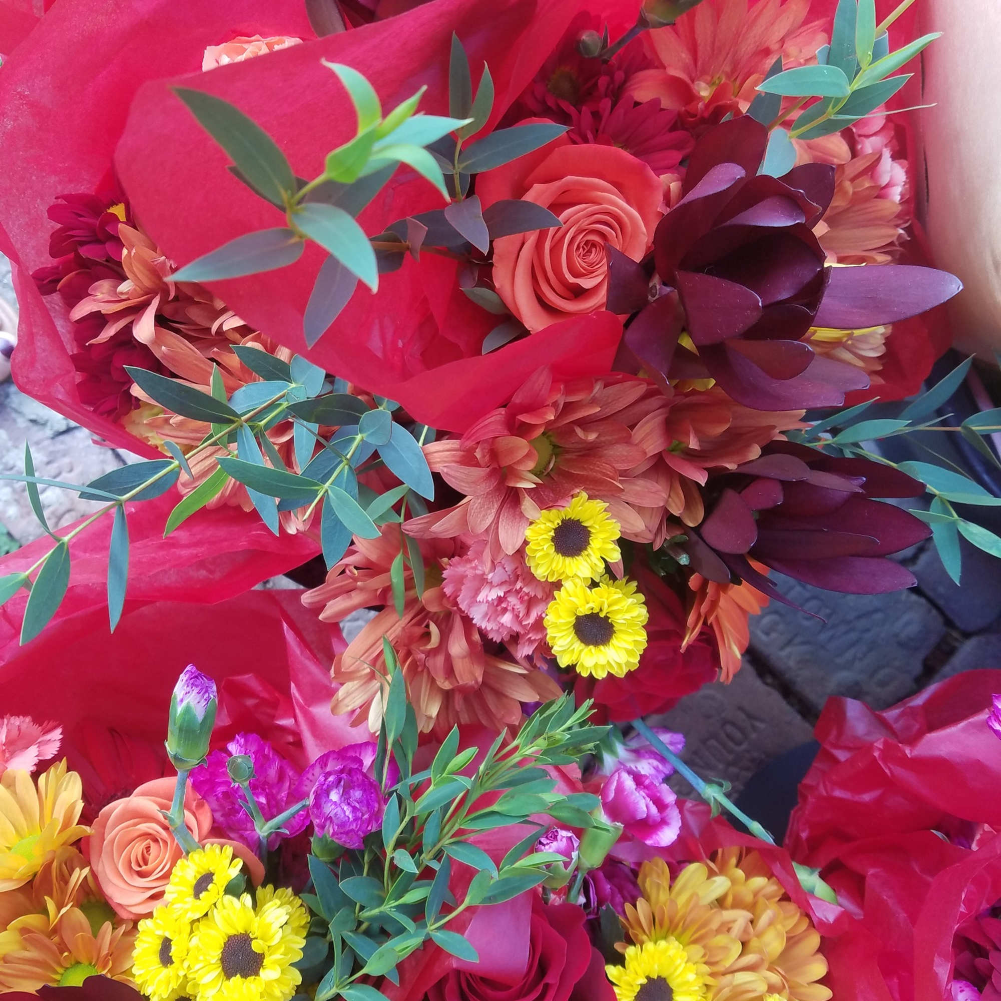 Bright mixed bouquets with roses and daisies wrapped in red paper