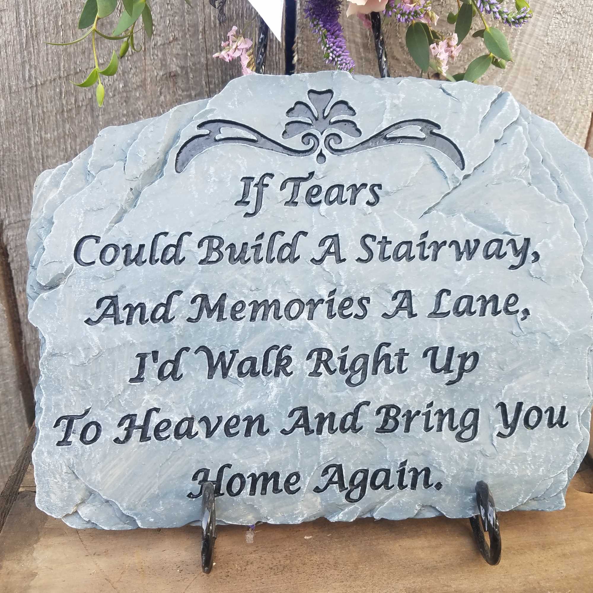 A memorial stone plaque with a sympathy quote on a stand.