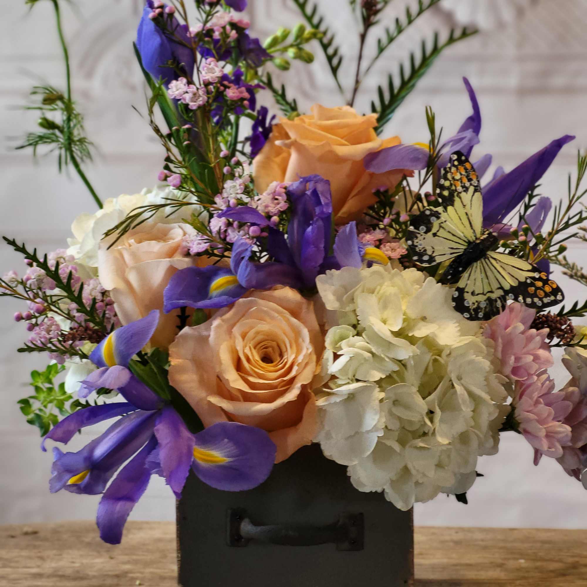 Bouquet of peach roses, purple irises, and white hydrangea in a black box