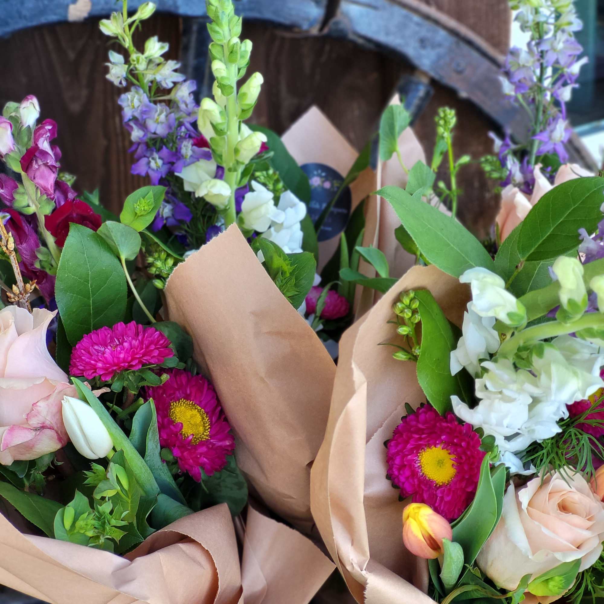 Mixed bouquets with pink roses, snapdragons, and magenta daisies in kraft paper
