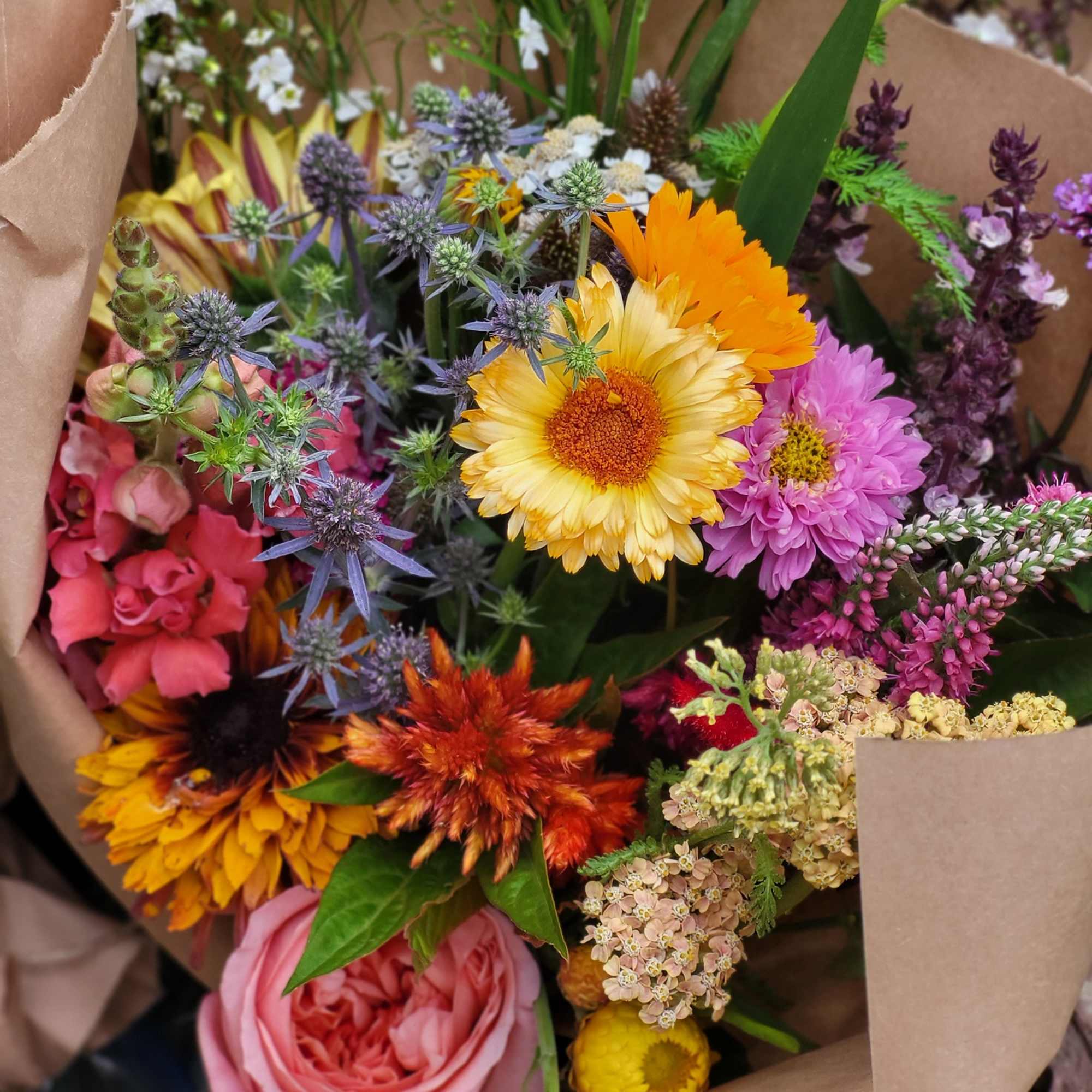 Mixed bouquet of colorful flowers wrapped in brown paper