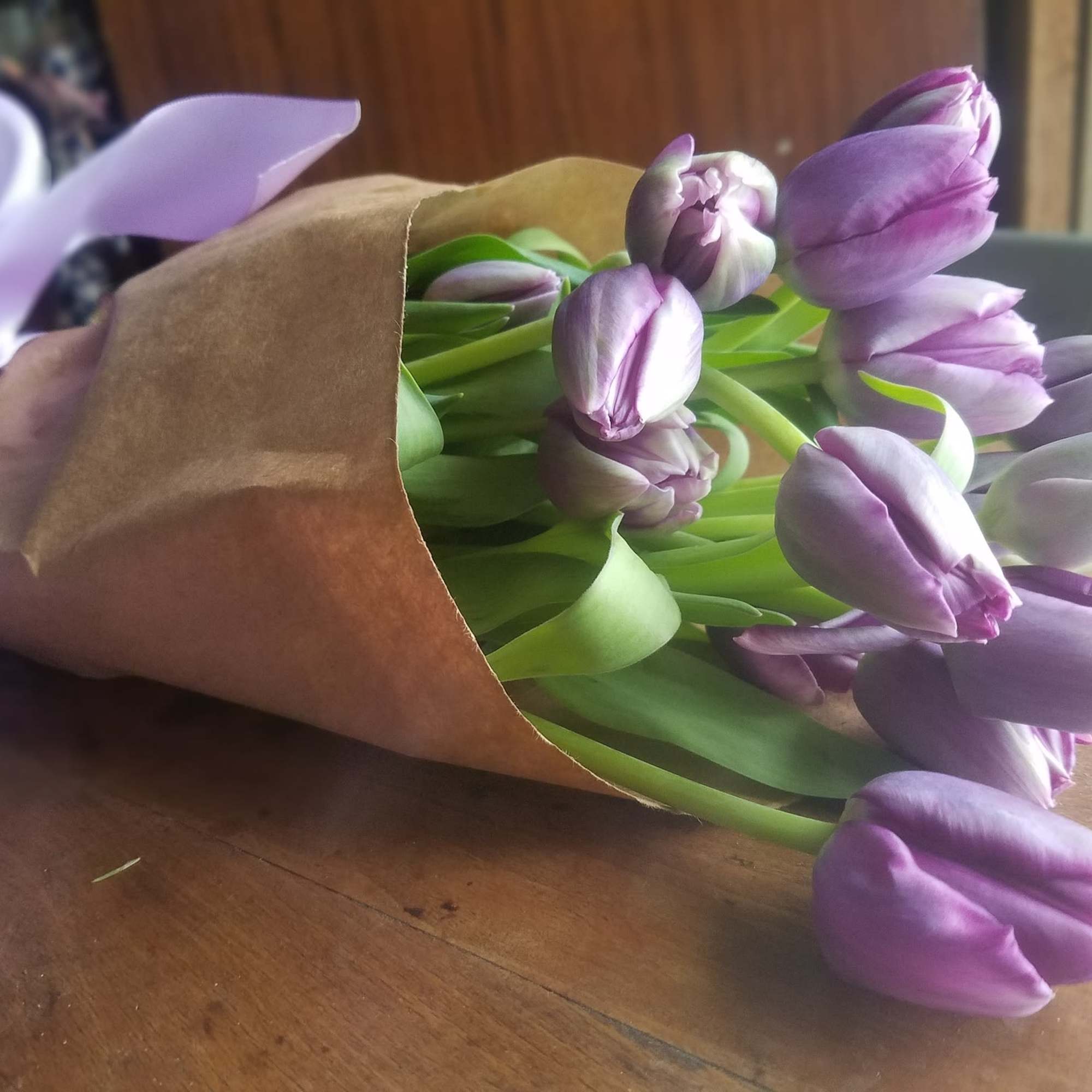 Bouquet of purple tulips wrapped in brown paper with a lavender ribbon