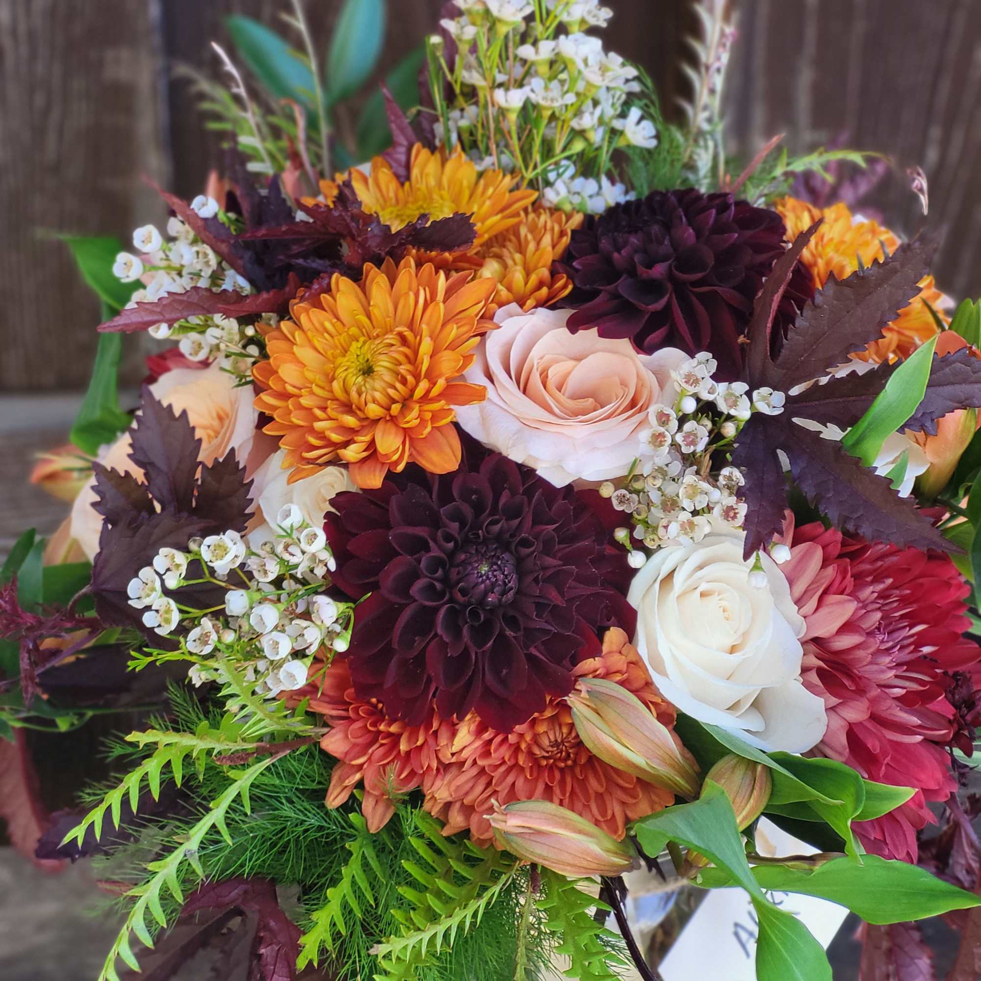 Bouquet of orange, burgundy, and white flowers with greenery