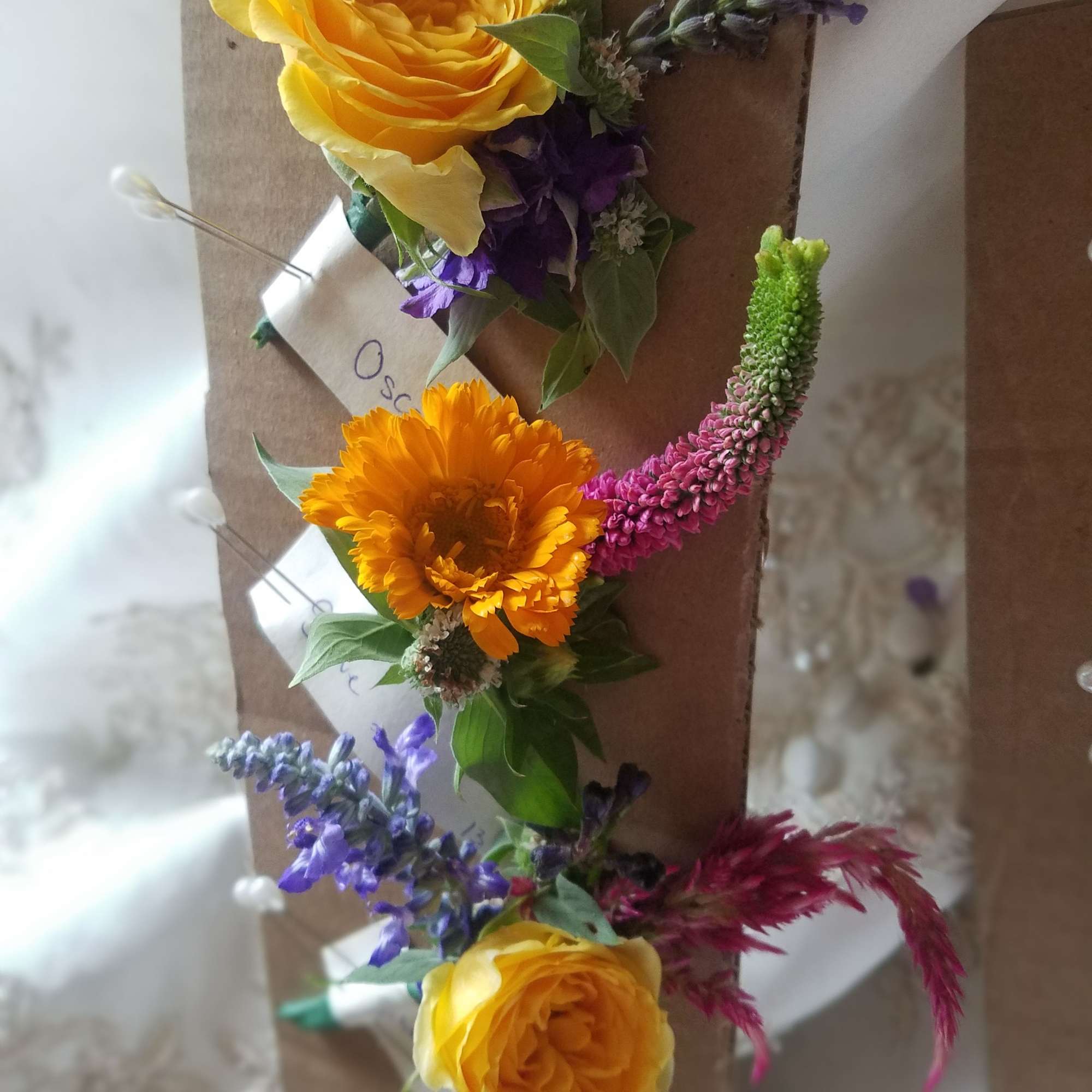 Floral corsages with yellow roses and purple accents on brown backing