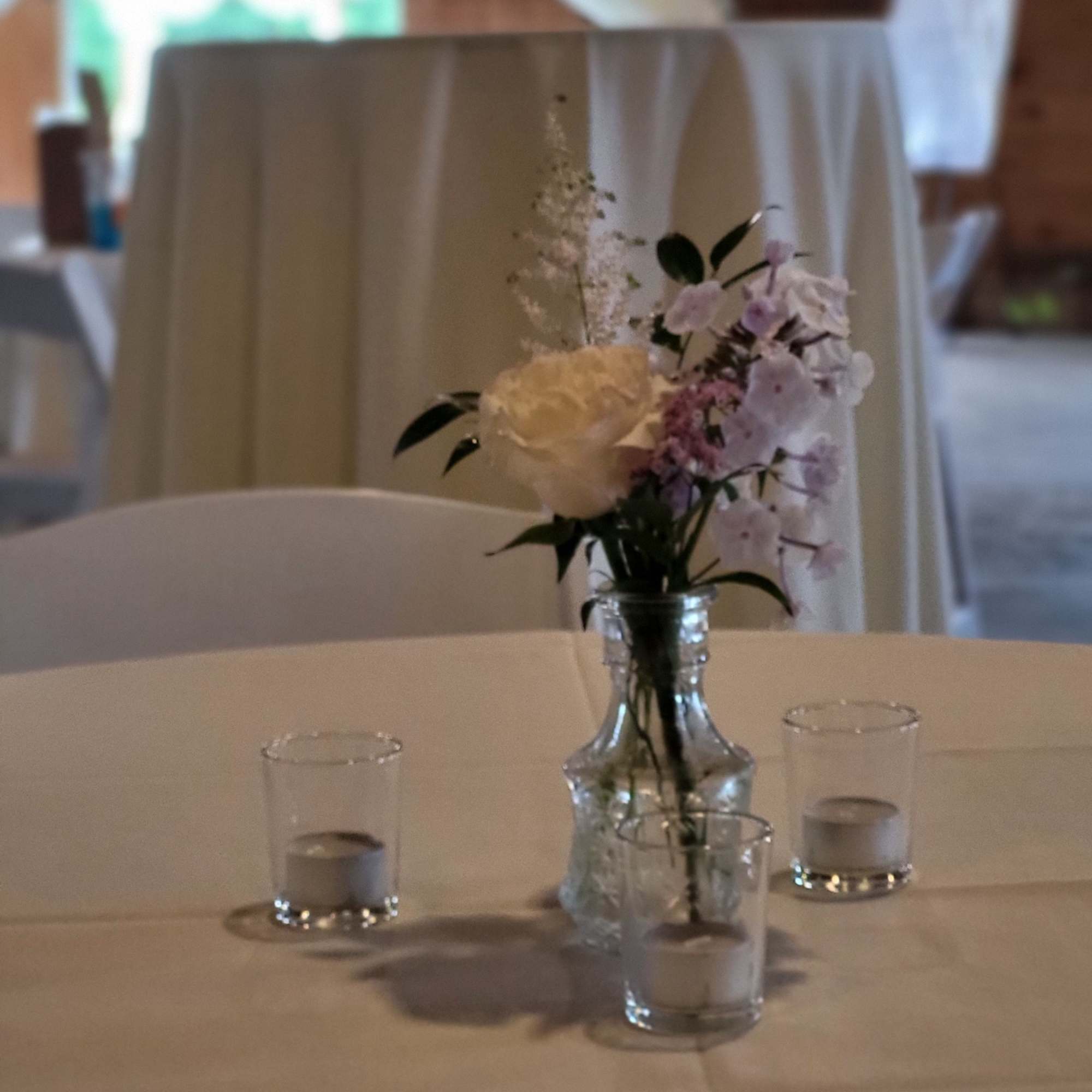 Small floral centerpiece in a clear glass vase on a table with candles
