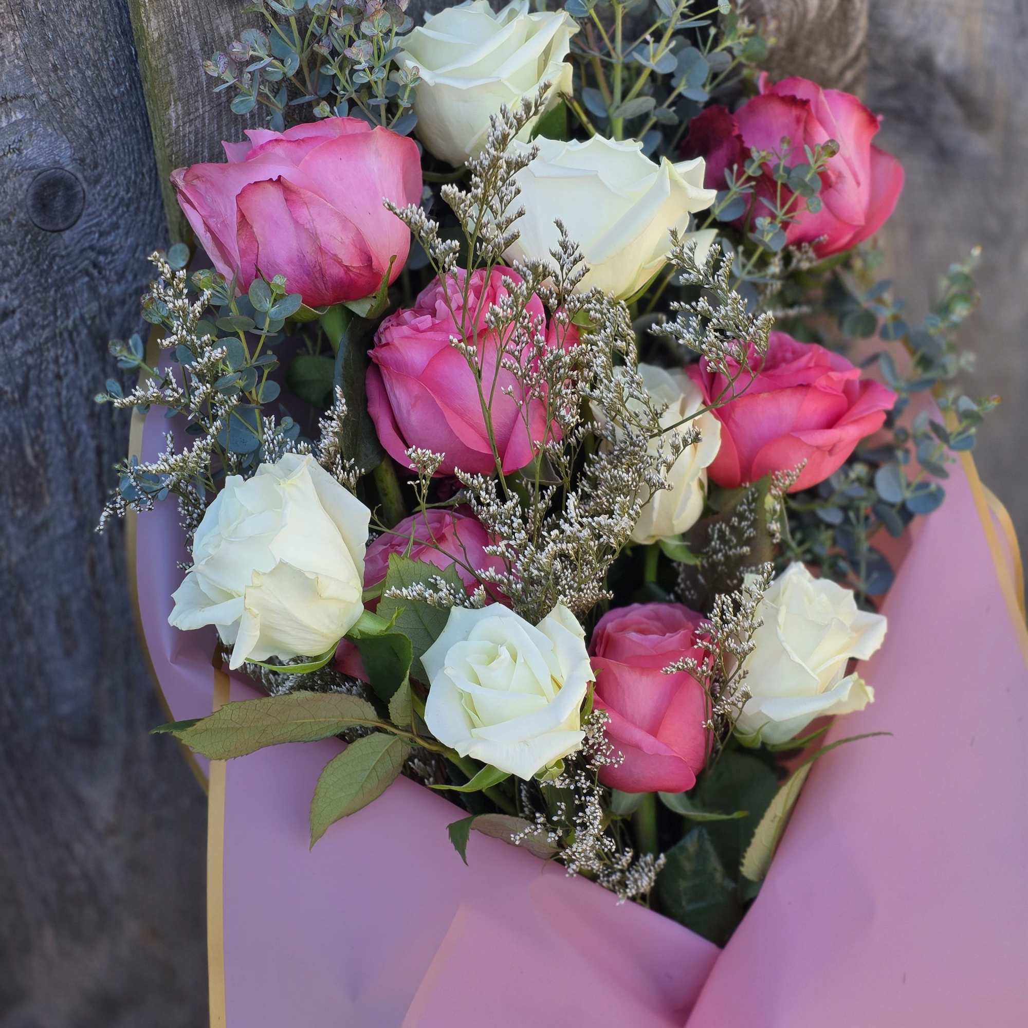 Bouquet of pink and white roses wrapped in pink paper