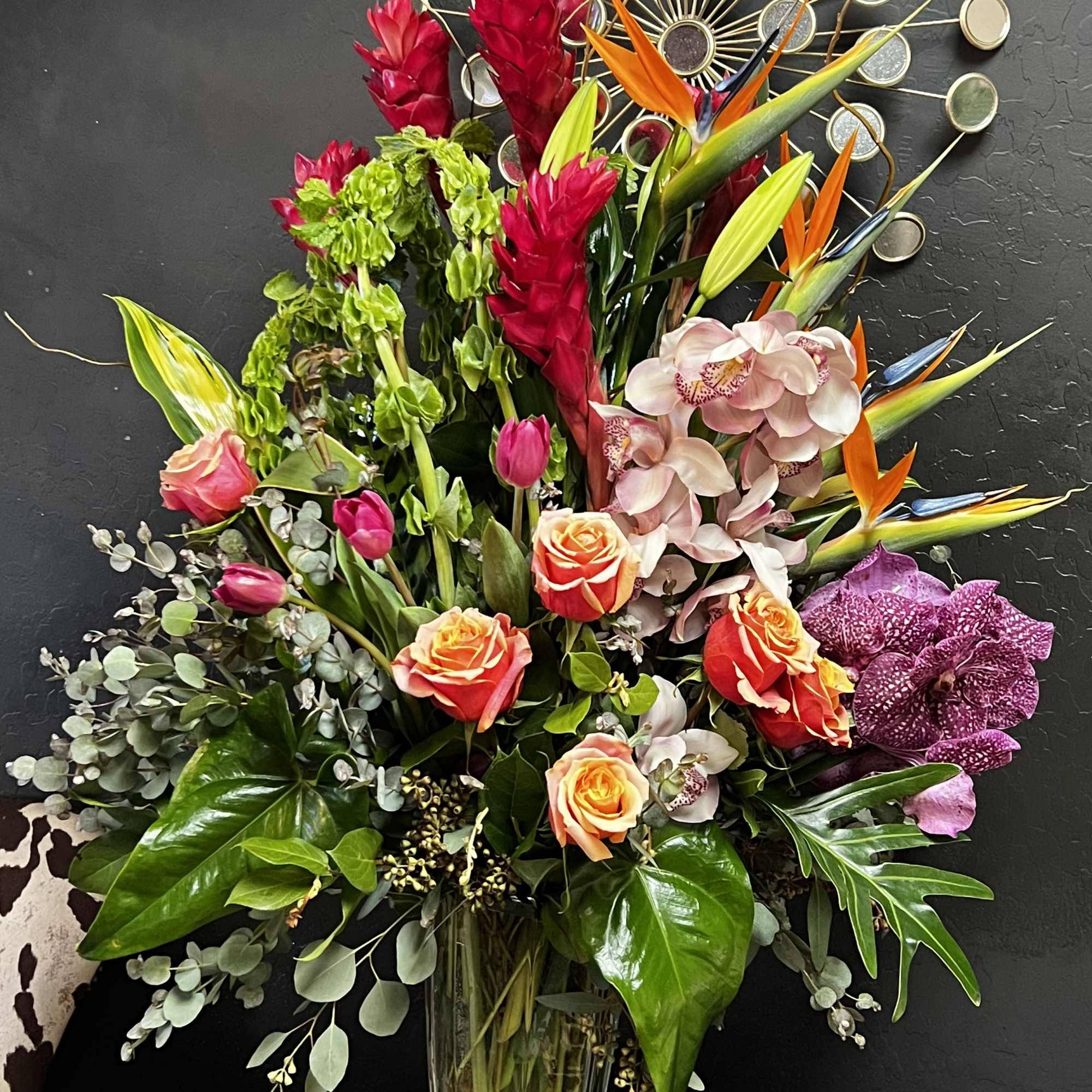 Tropical bouquet with roses, orchids, and bird-of-paradise in a glass vase