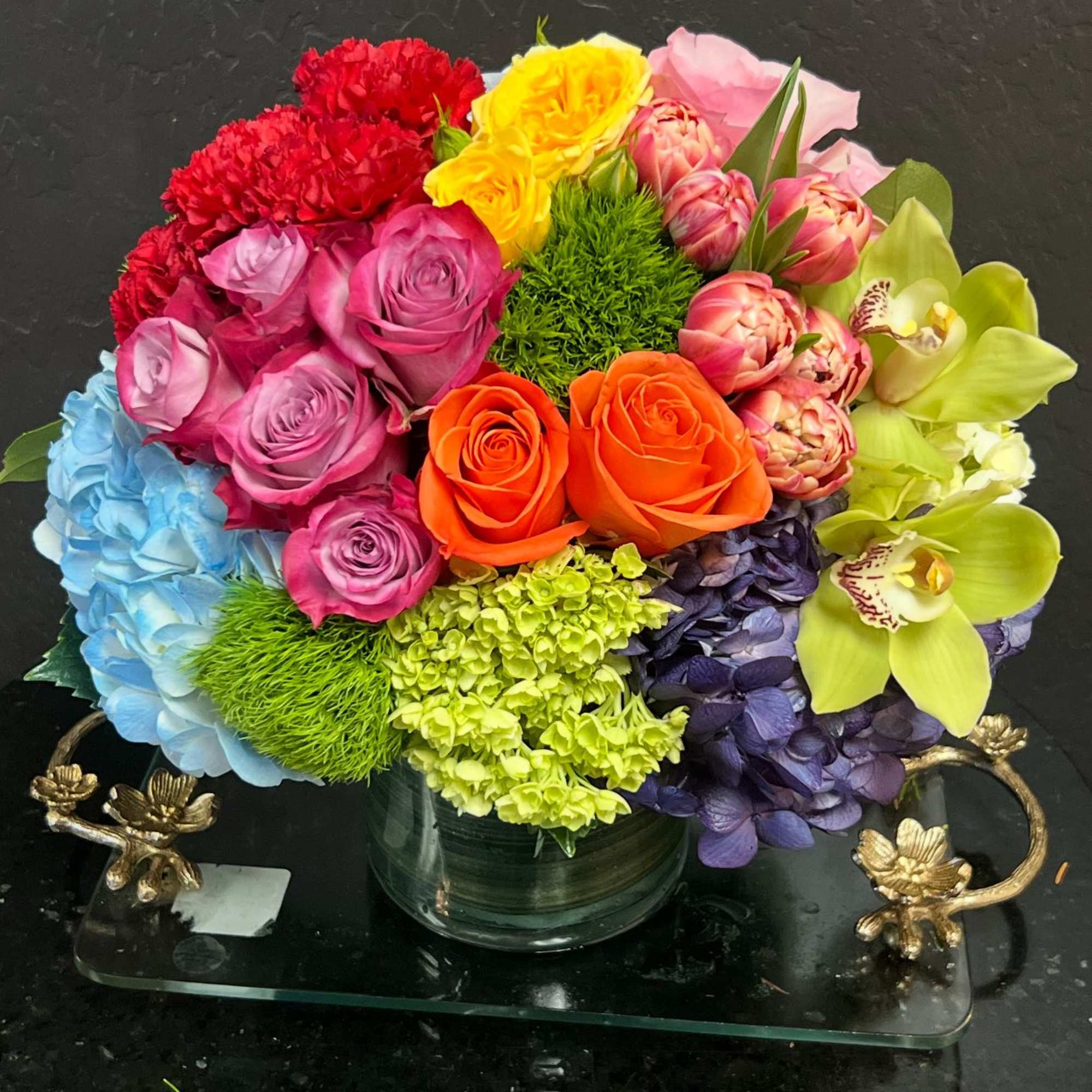 Colorful bouquet of roses, hydrangeas, and orchids in a glass vase