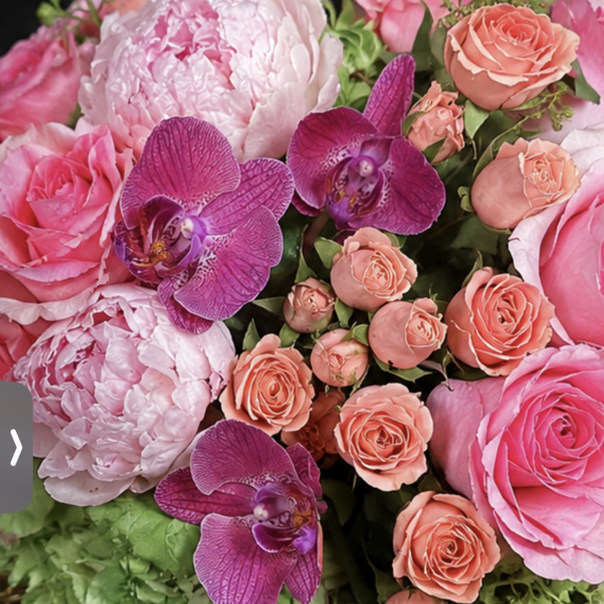 Pink and peach floral arrangement with orchids and roses in a vase
