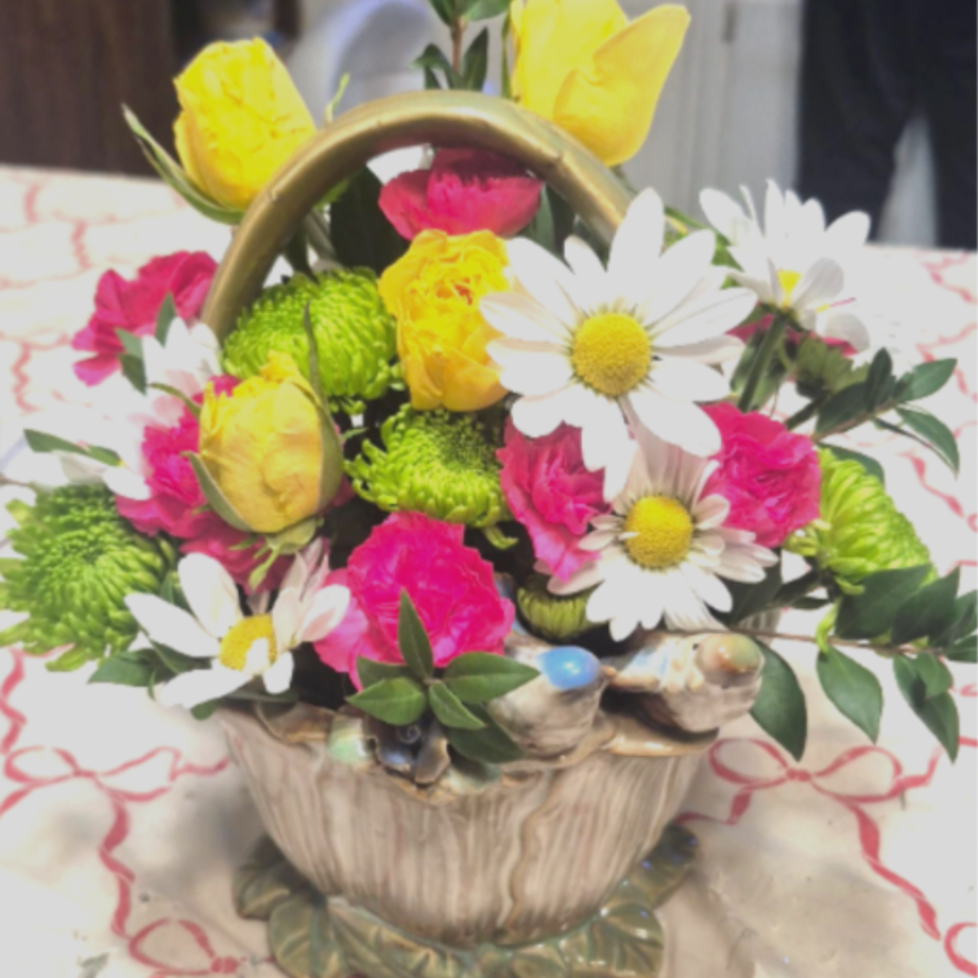 Bright mixed flower arrangement in a ceramic basket with handle