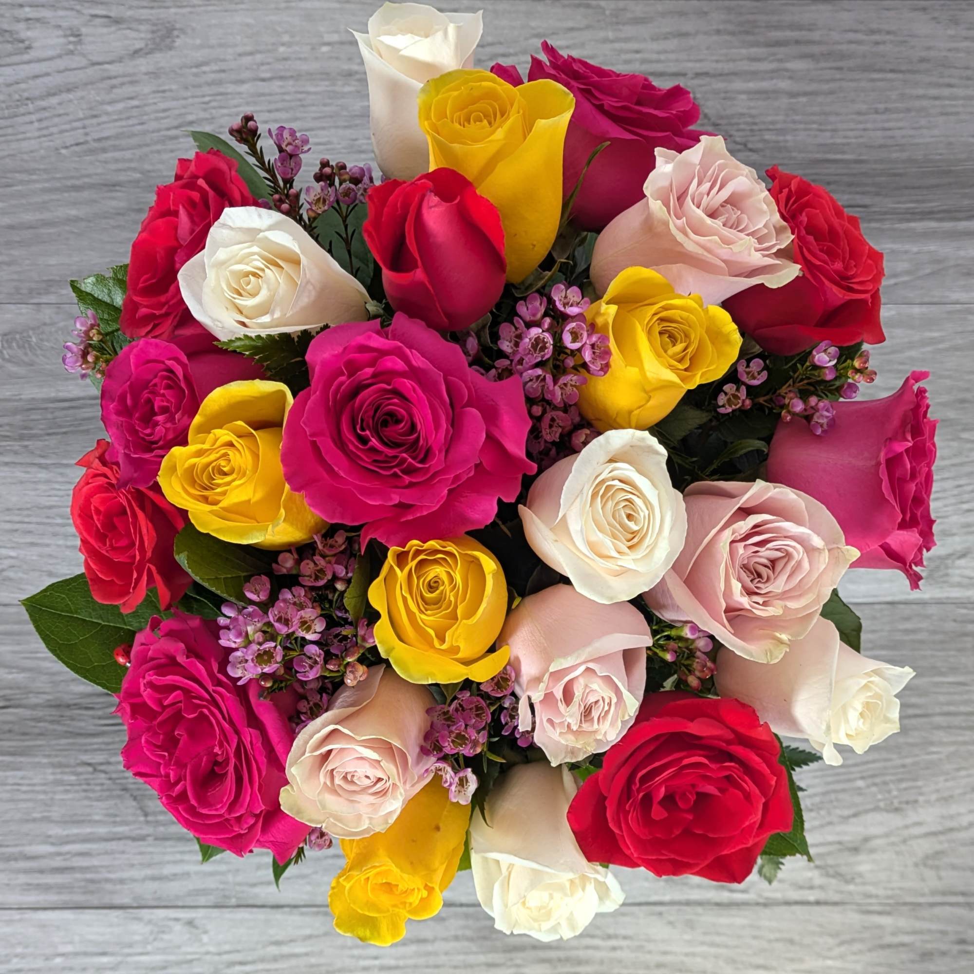 Mixed bouquet of multicolored roses with small purple filler flowers