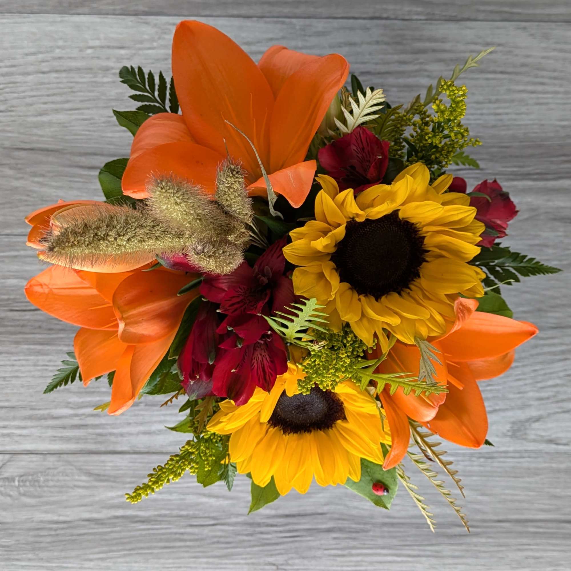 Bouquet with orange lilies, yellow sunflowers, and burgundy flowers