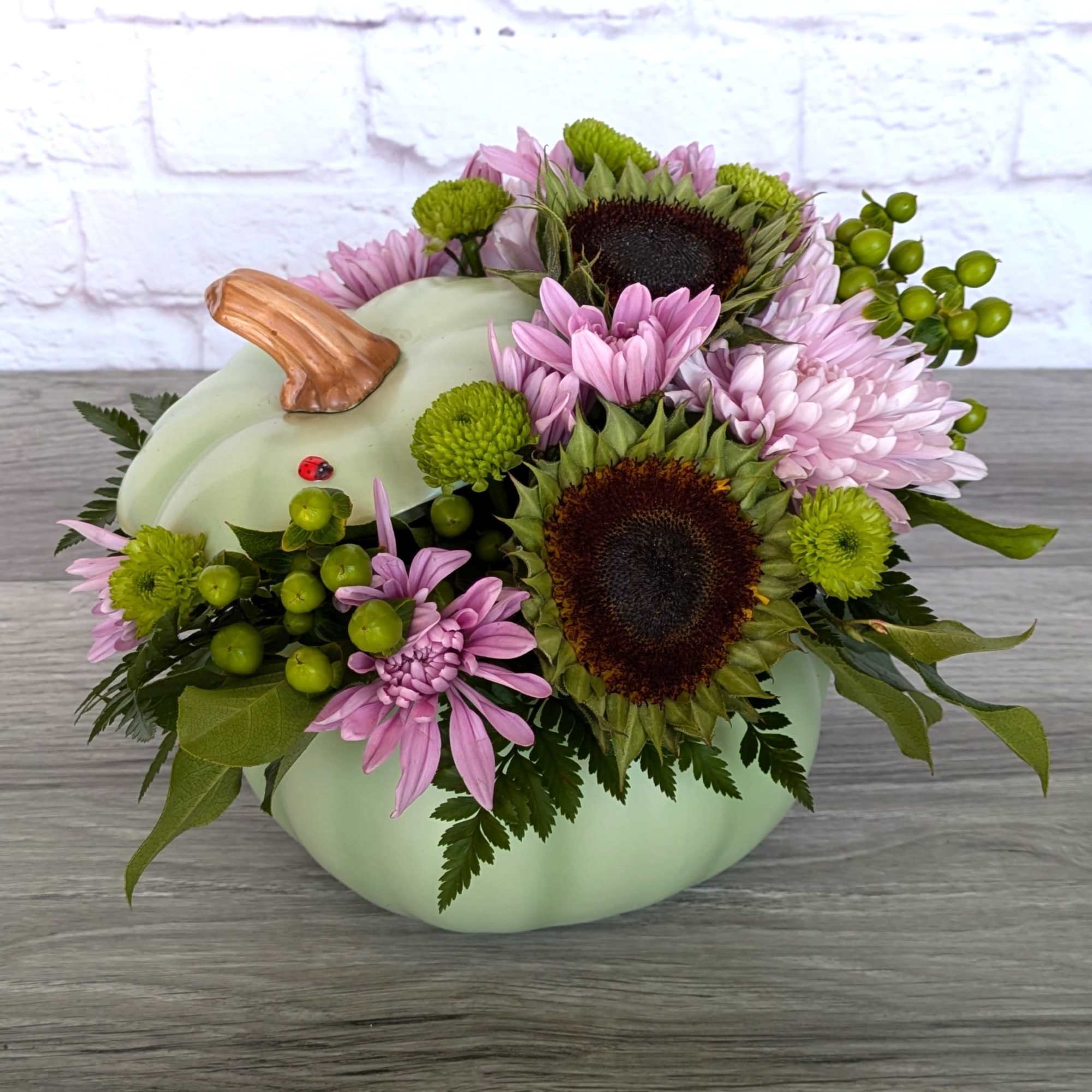 Pumpkin-shaped floral arrangement with pink daisies and green berries