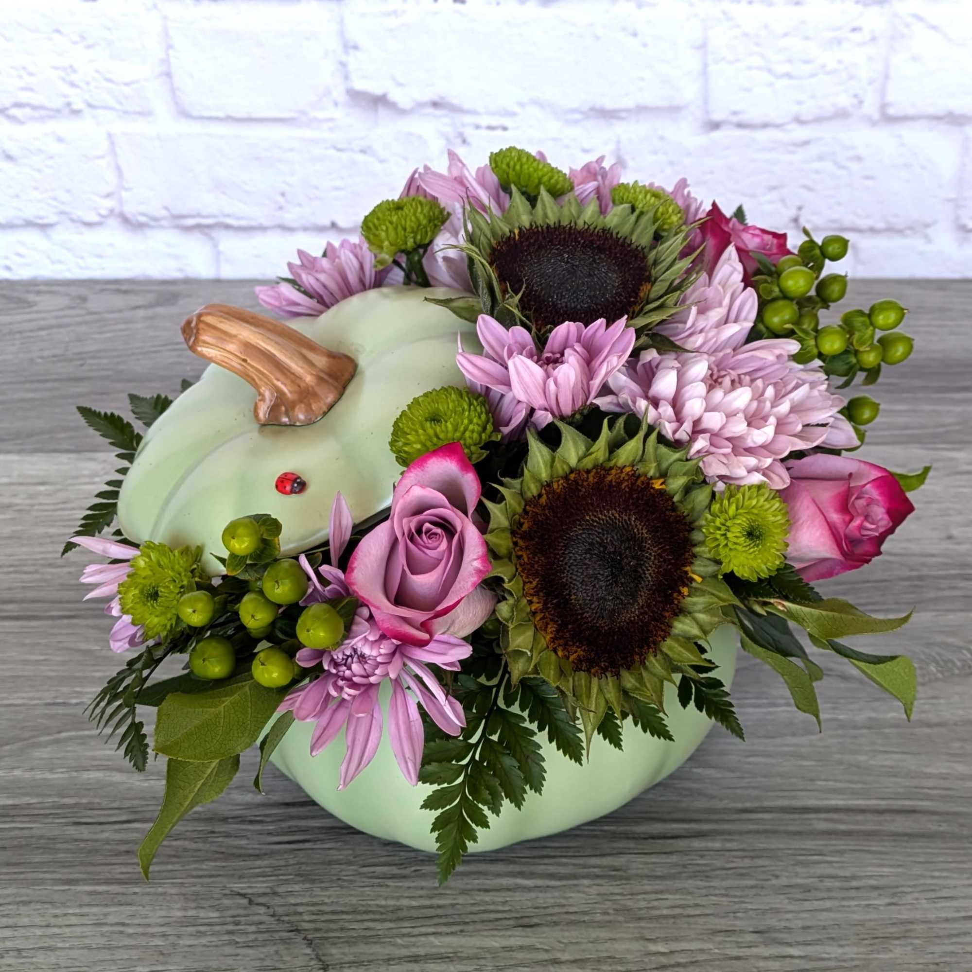 Pumpkin-shaped floral arrangement with pink roses and purple daisies
