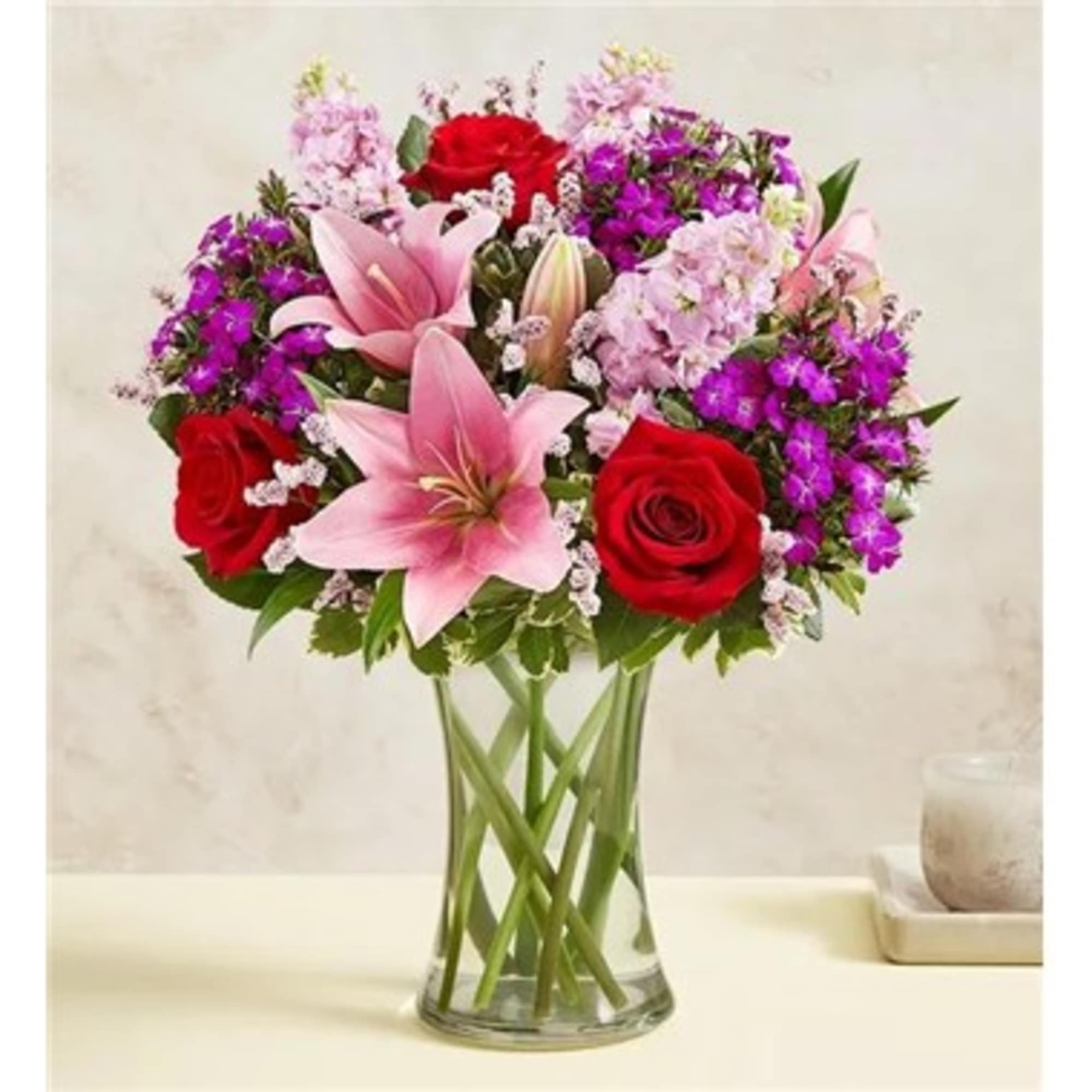 Bouquet of pink lilies and red roses in a clear glass vase