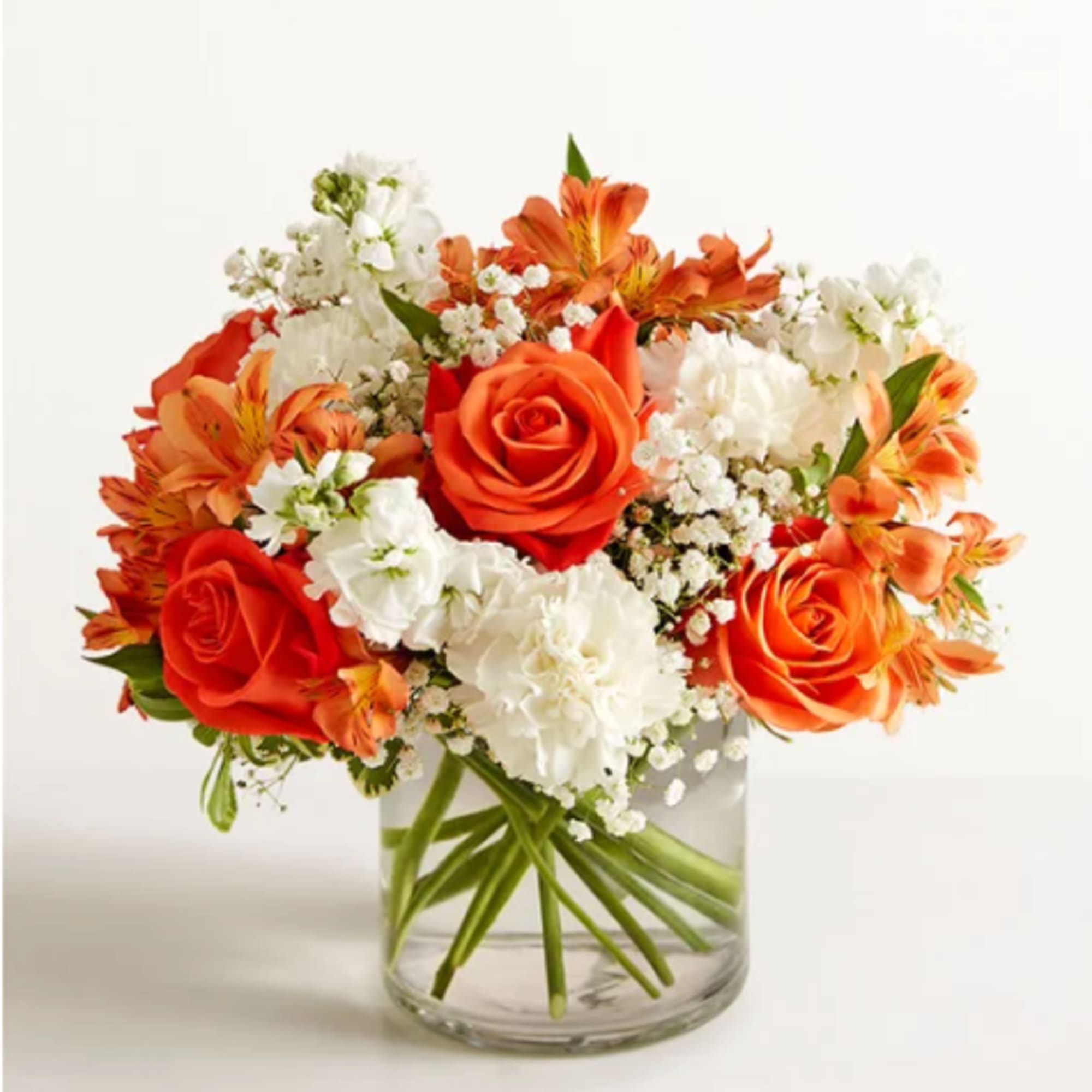 Orange and white flowers arranged in a clear glass vase