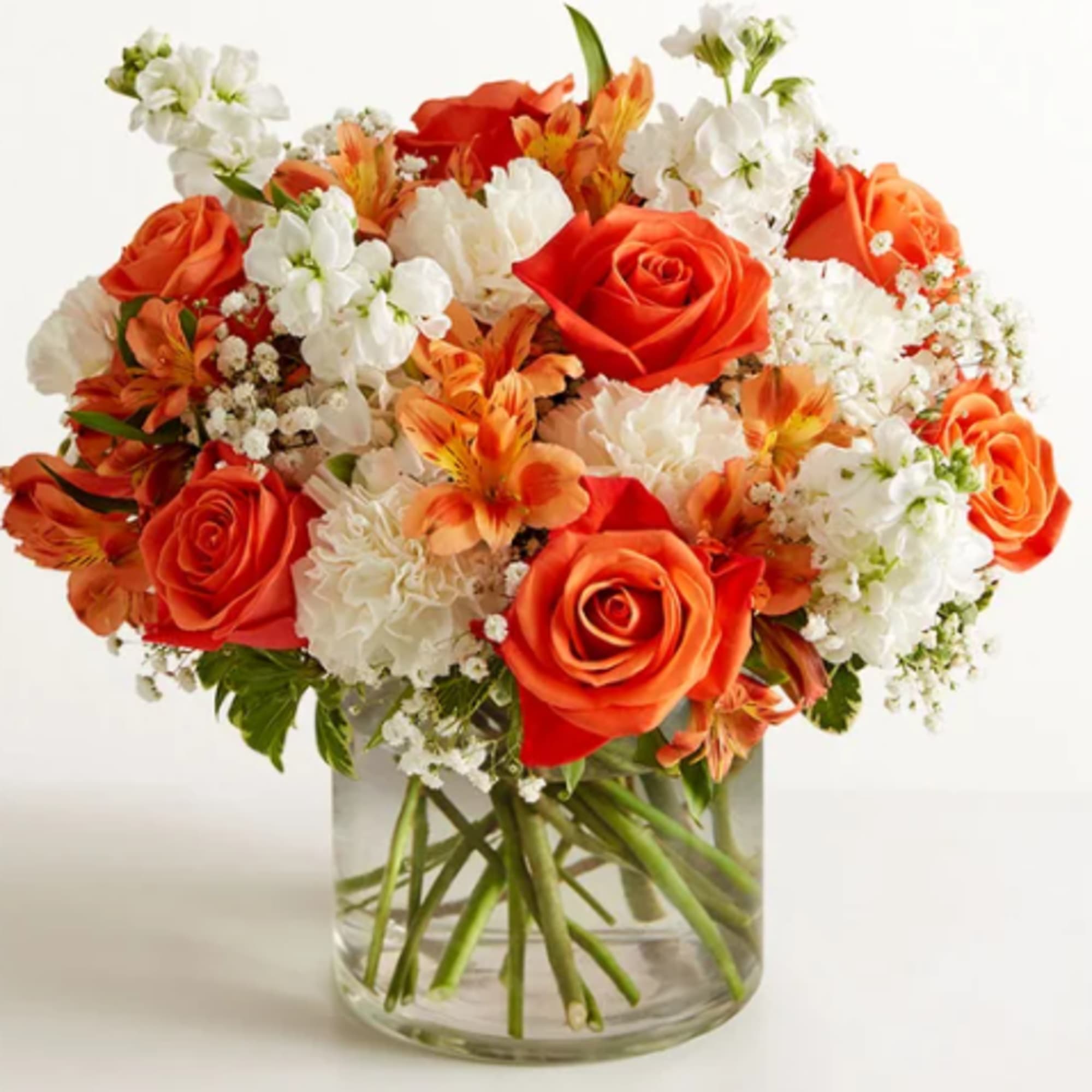 Orange and white roses arranged in a clear glass vase