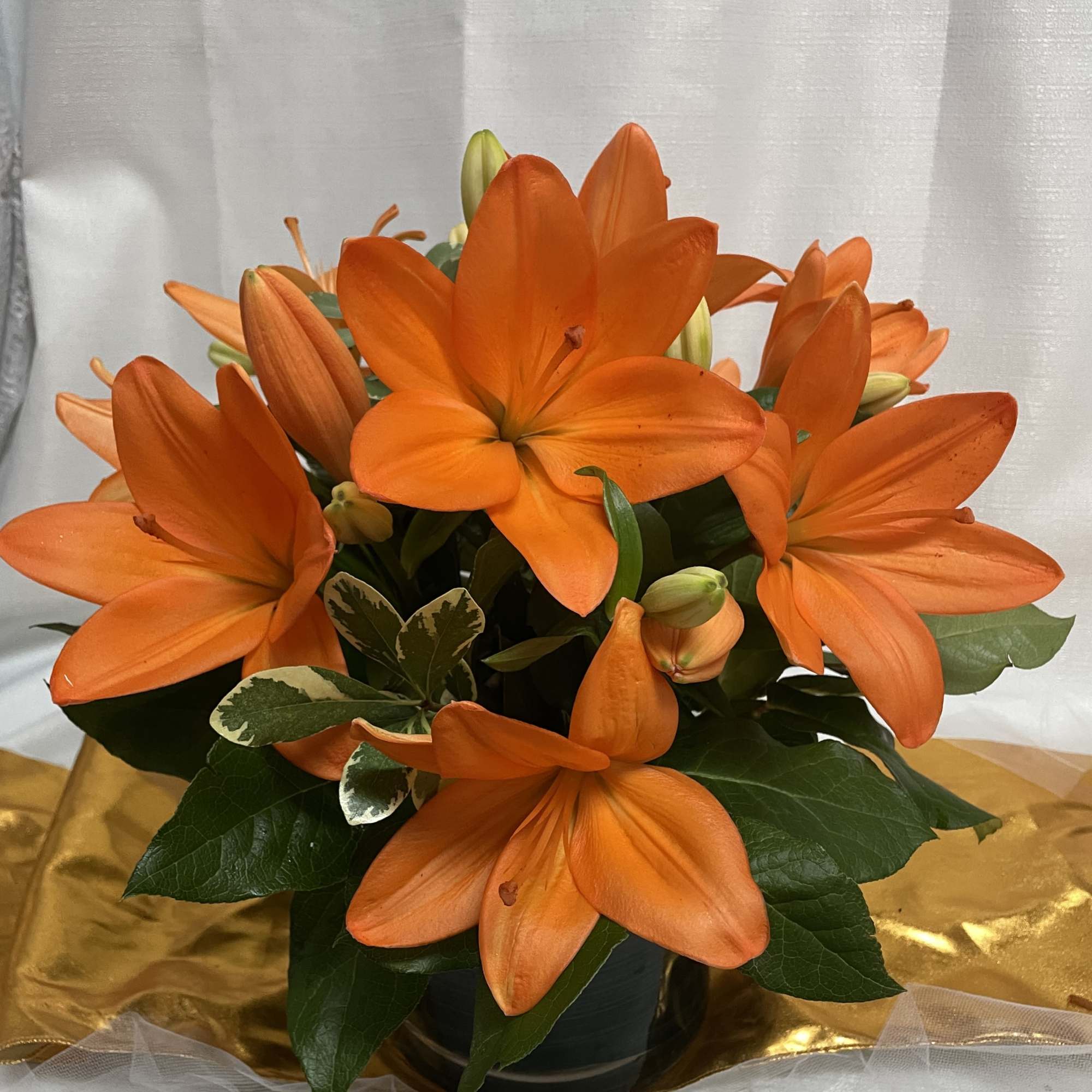 Orange lilies arranged in a dark vase