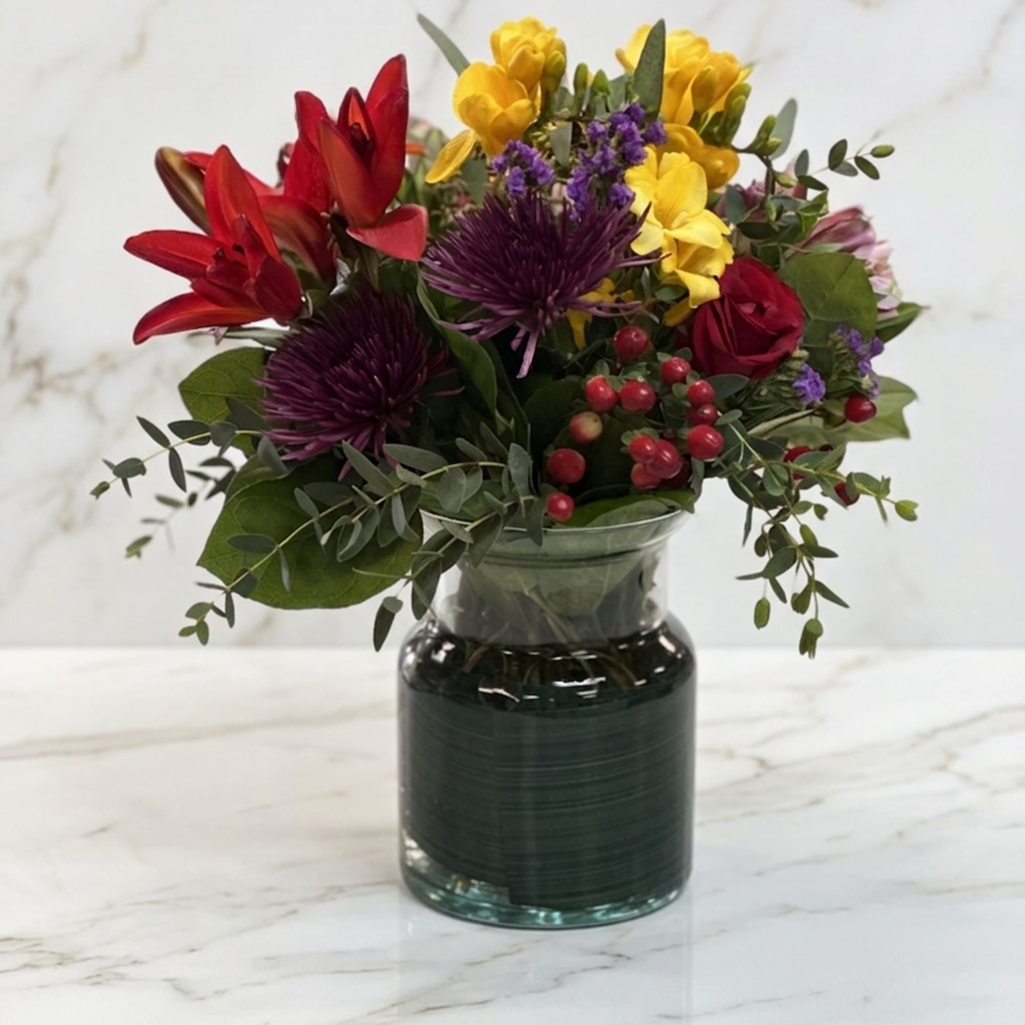 Celebrate rich colors in a charming vase. Featuring deep red blooms, sunny