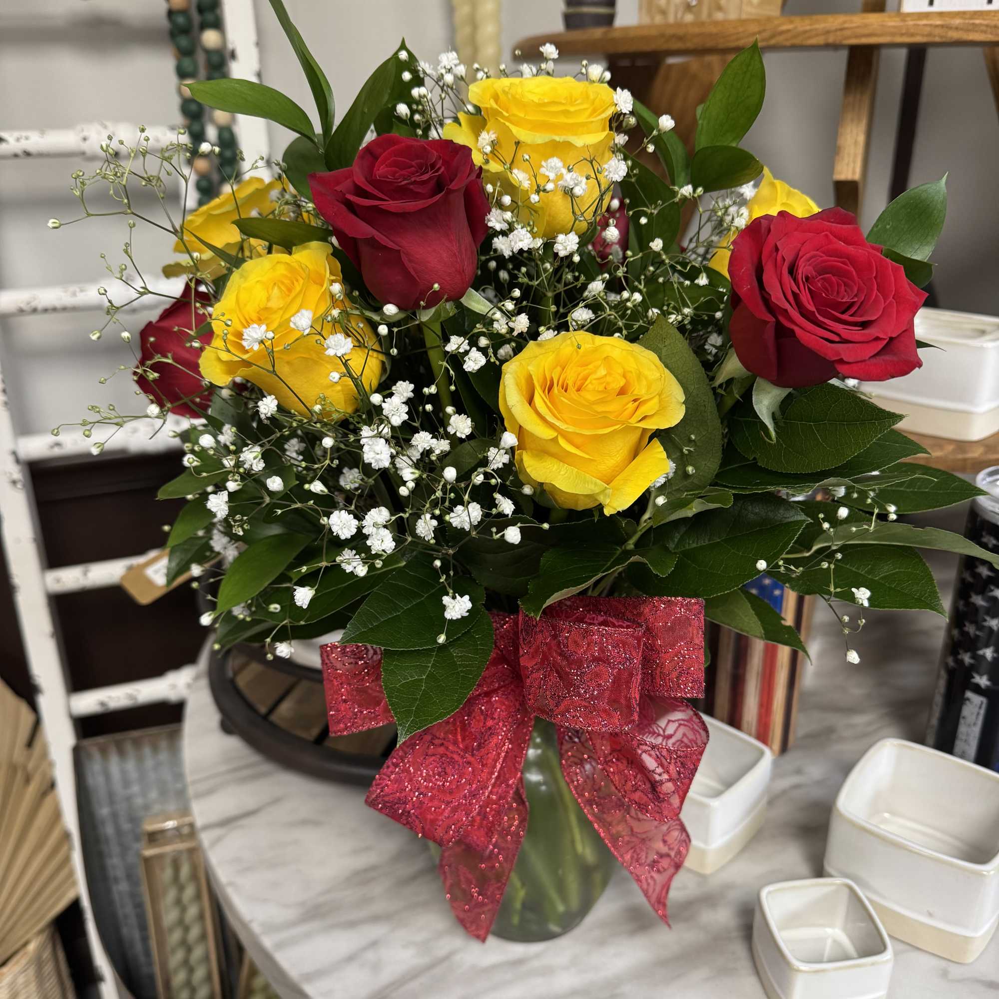 Bouquet of red and yellow roses in a glass vase with a pink ribbon