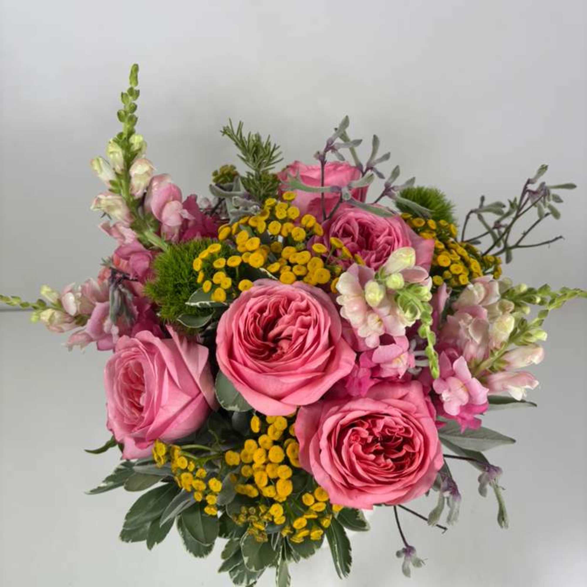 Pink roses with yellow filler flowers in a hand-tied bouquet