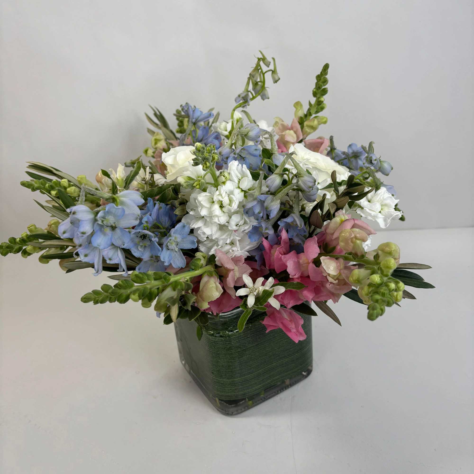 Mixed pastel flower arrangement in a square glass vase