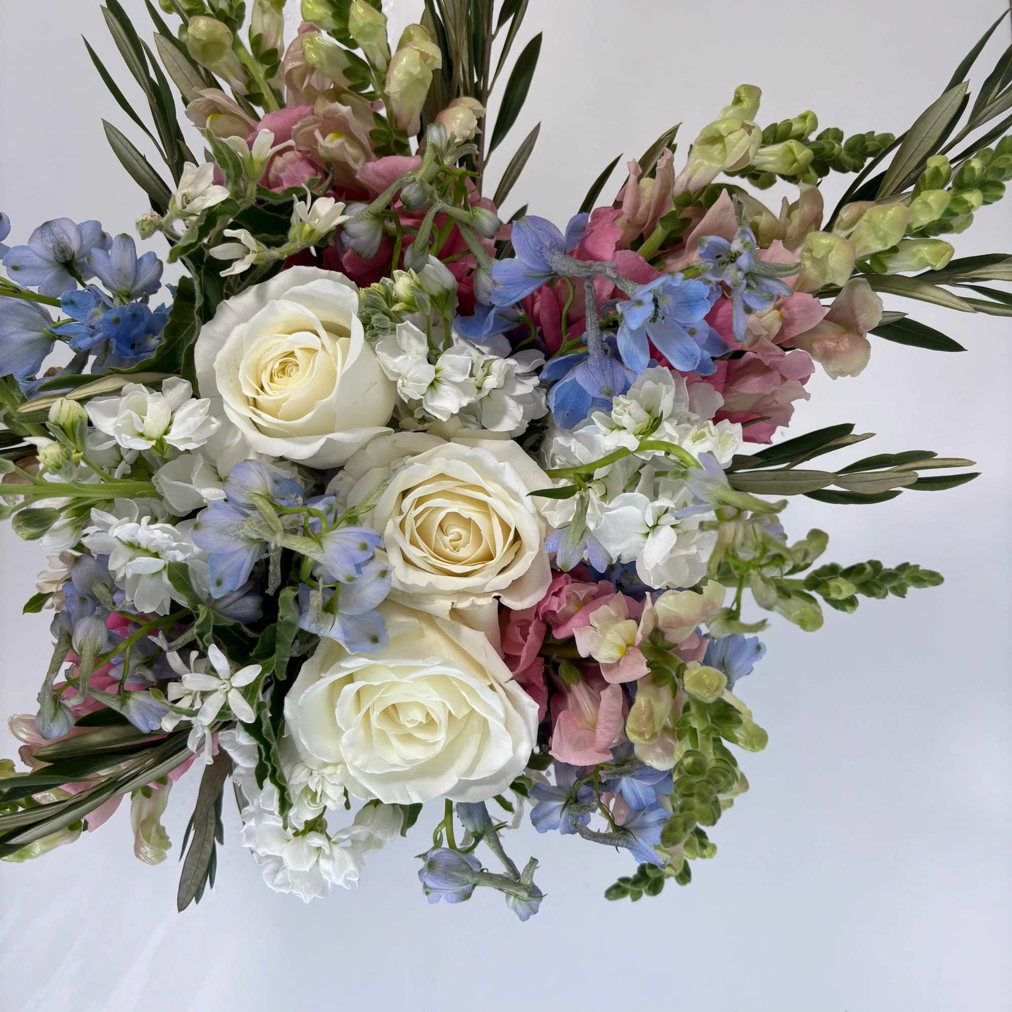 Bouquet of white roses, blue flowers, and pink blooms