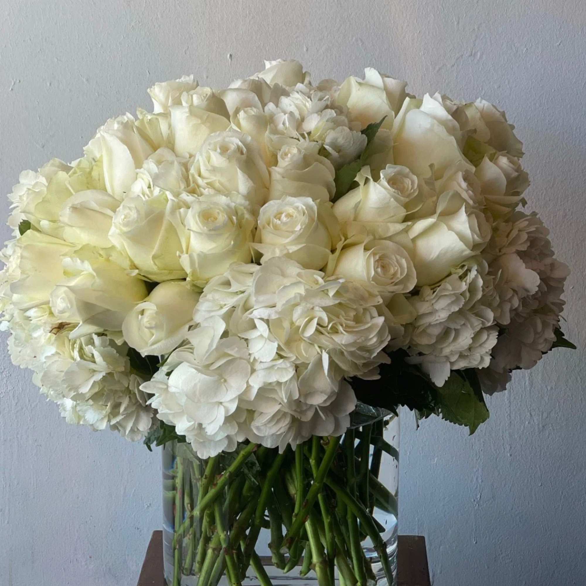 White roses and hydrangeas arranged in a clear glass vase, photo 2 of 2