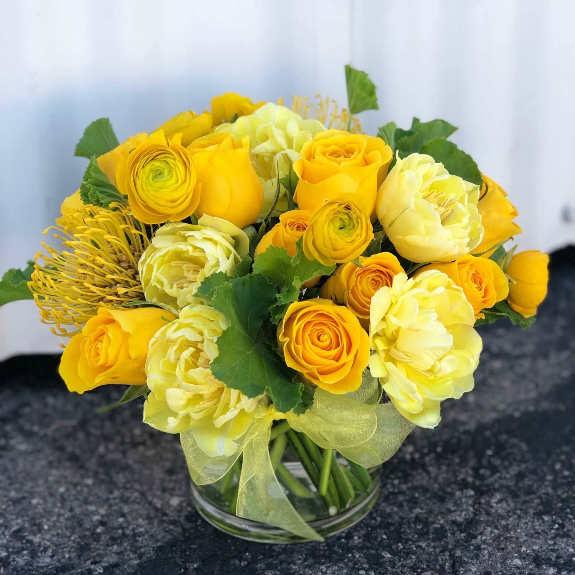 Yellow roses and pale blooms arranged in a clear glass vase, photo 2 of 2