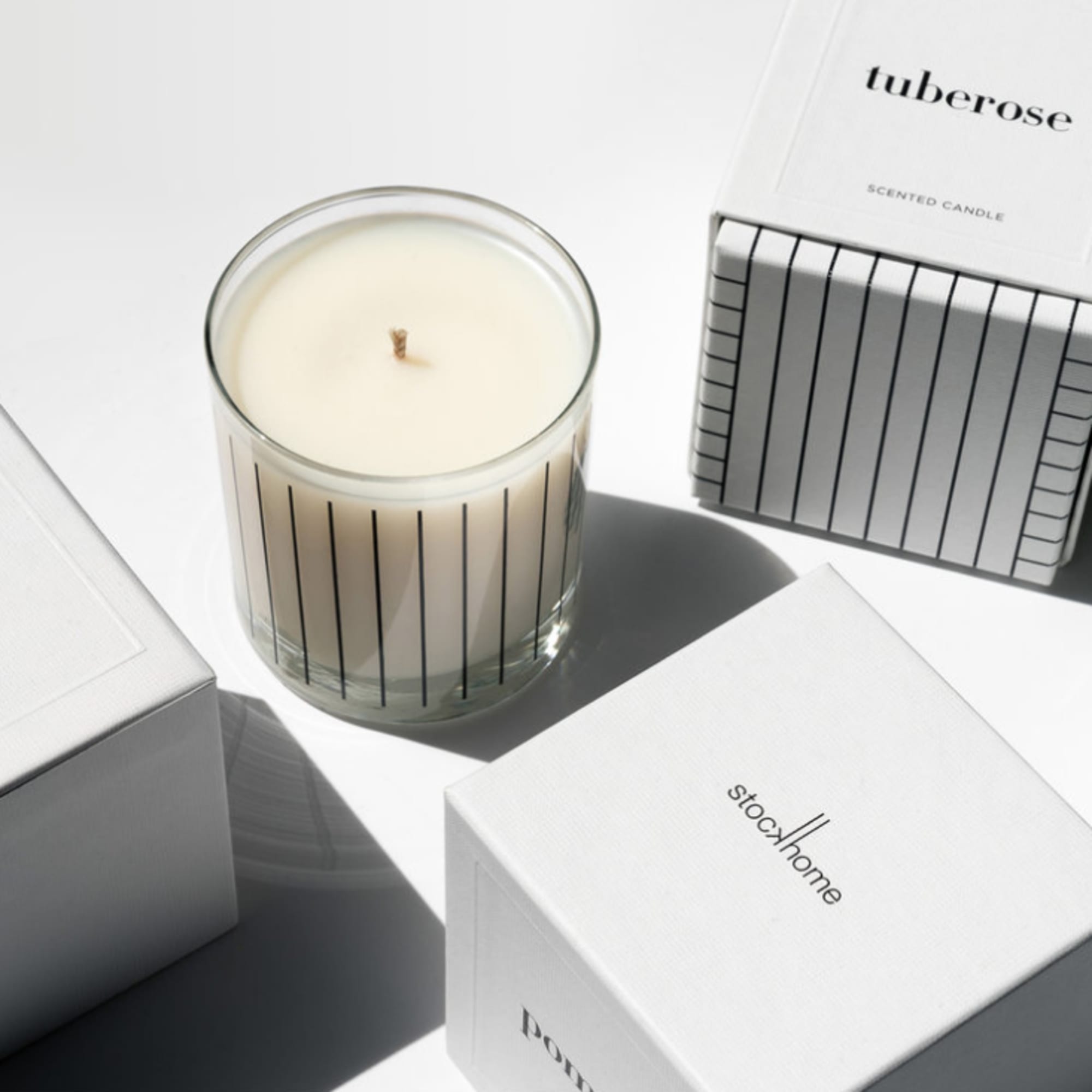 Scented candle in a glass jar beside white product boxes
