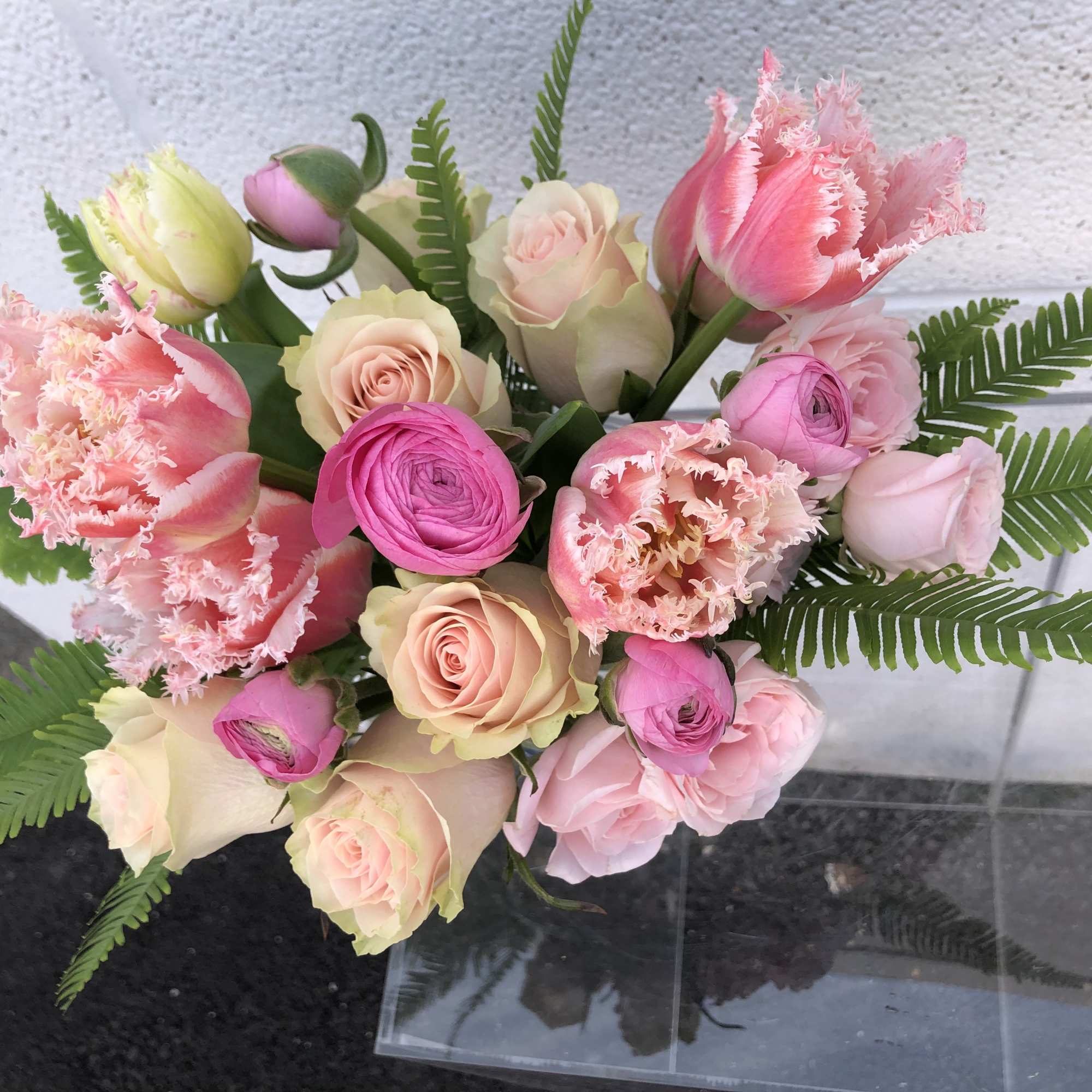 Bouquet of pink and cream roses with tulips and fern fronds