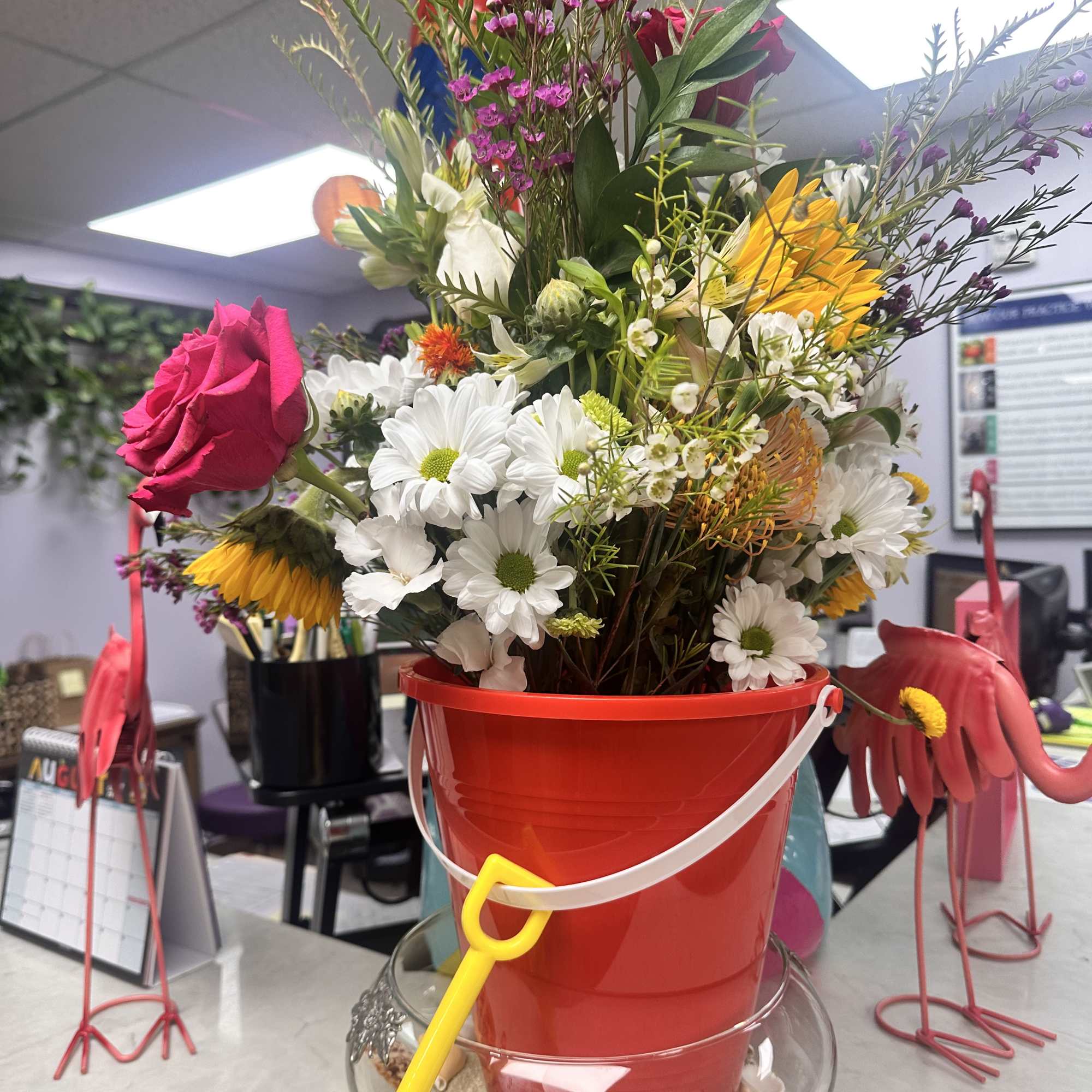 Mixed bouquet in a red bucket with a yellow shovel decoration