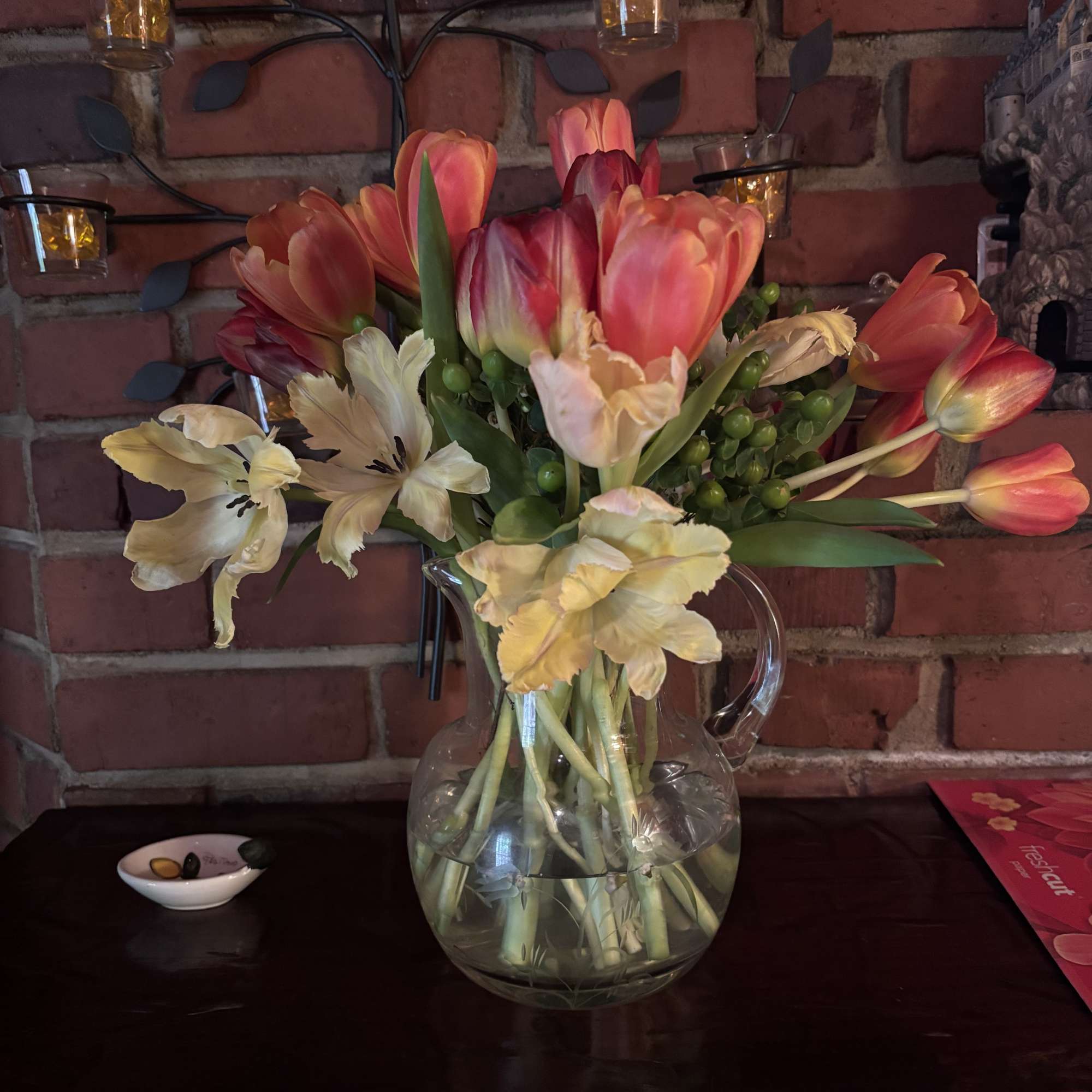 Tulip bouquet with pale cream flowers in a clear glass pitcher vase