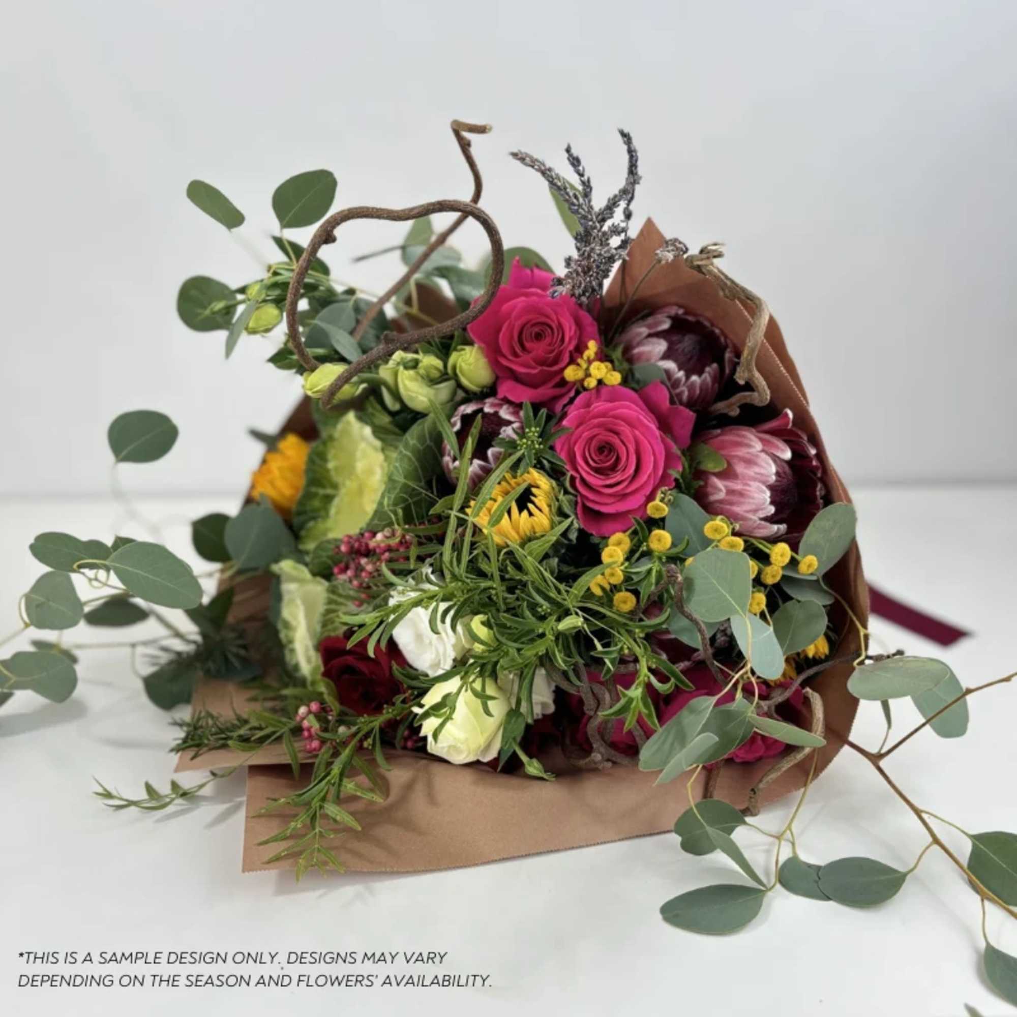 Bouquet of pink roses and mixed blooms wrapped in brown paper