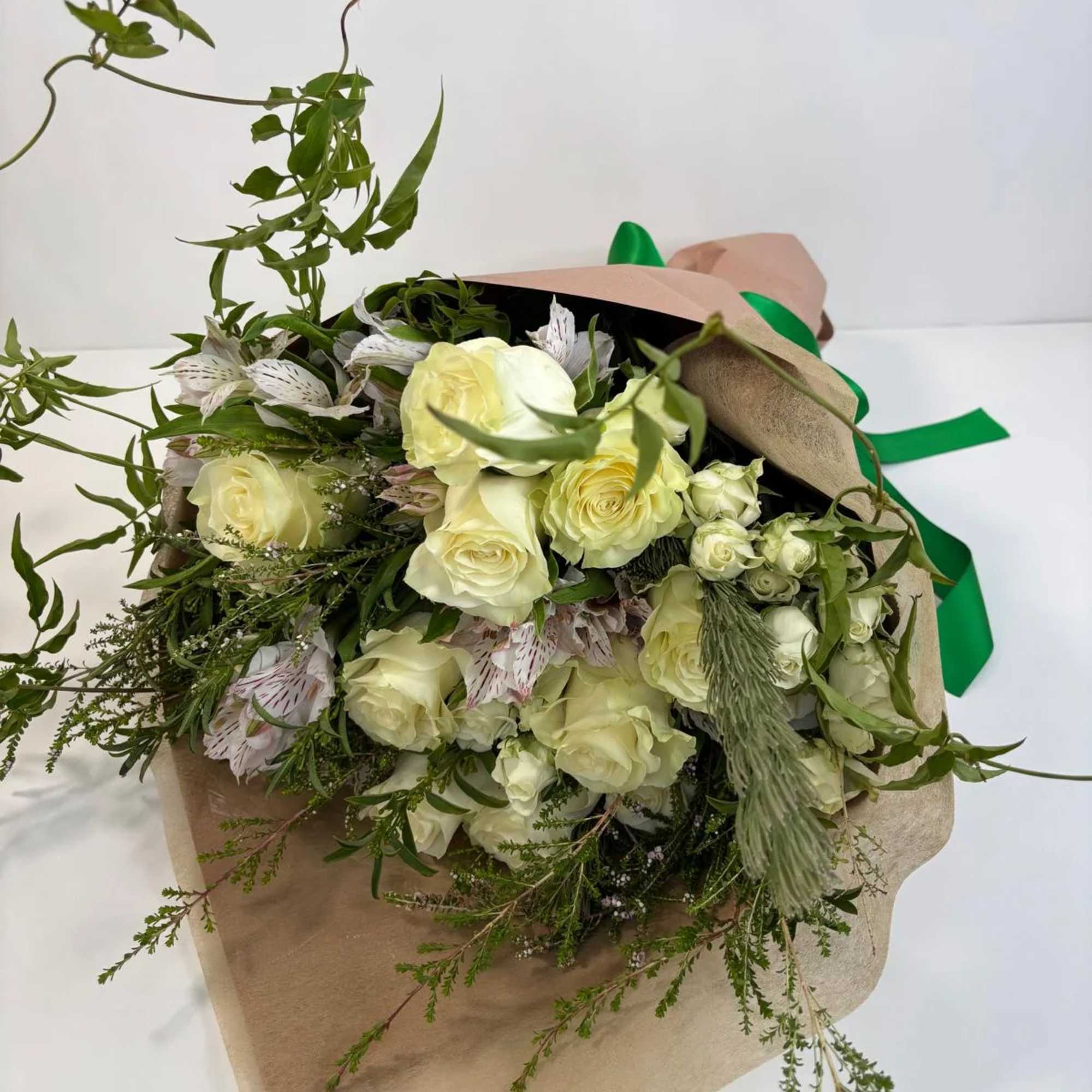 Bouquet of pale yellow roses with white flowers wrapped in brown paper