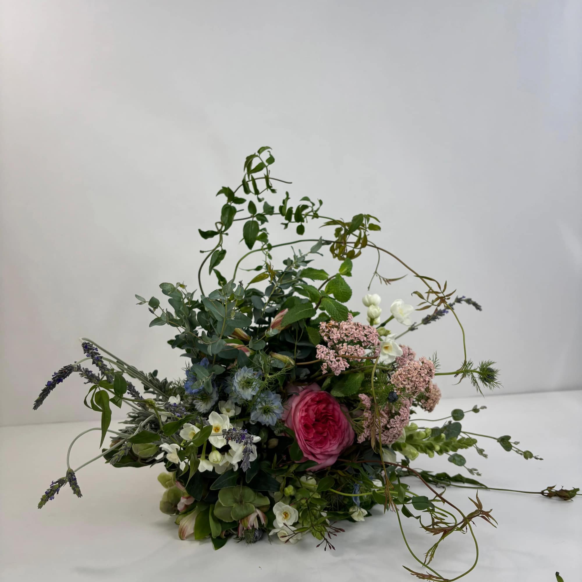 Loose floral arrangement with pink and white blooms and trailing greenery