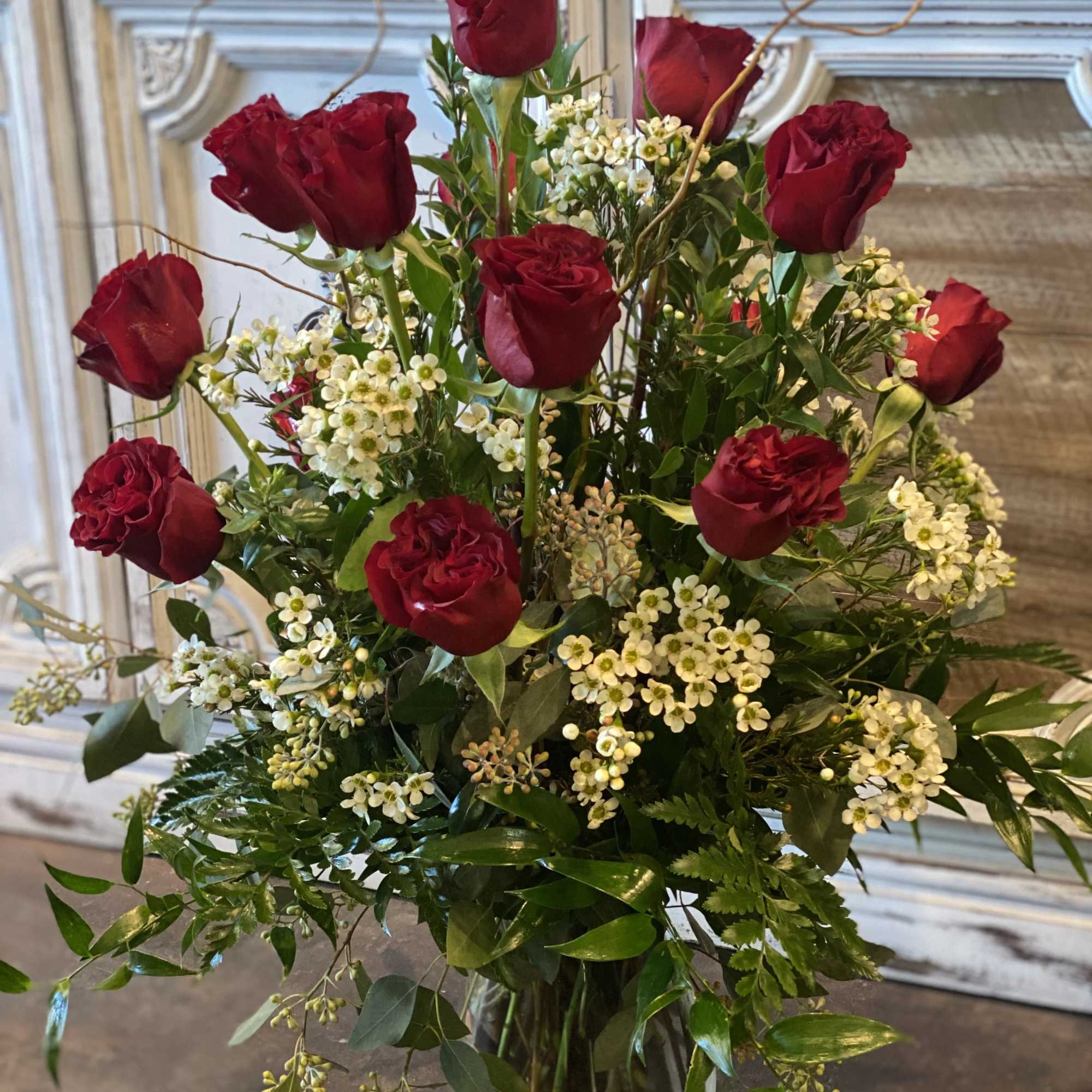 Red roses arranged in a clear glass vase with white filler flowers