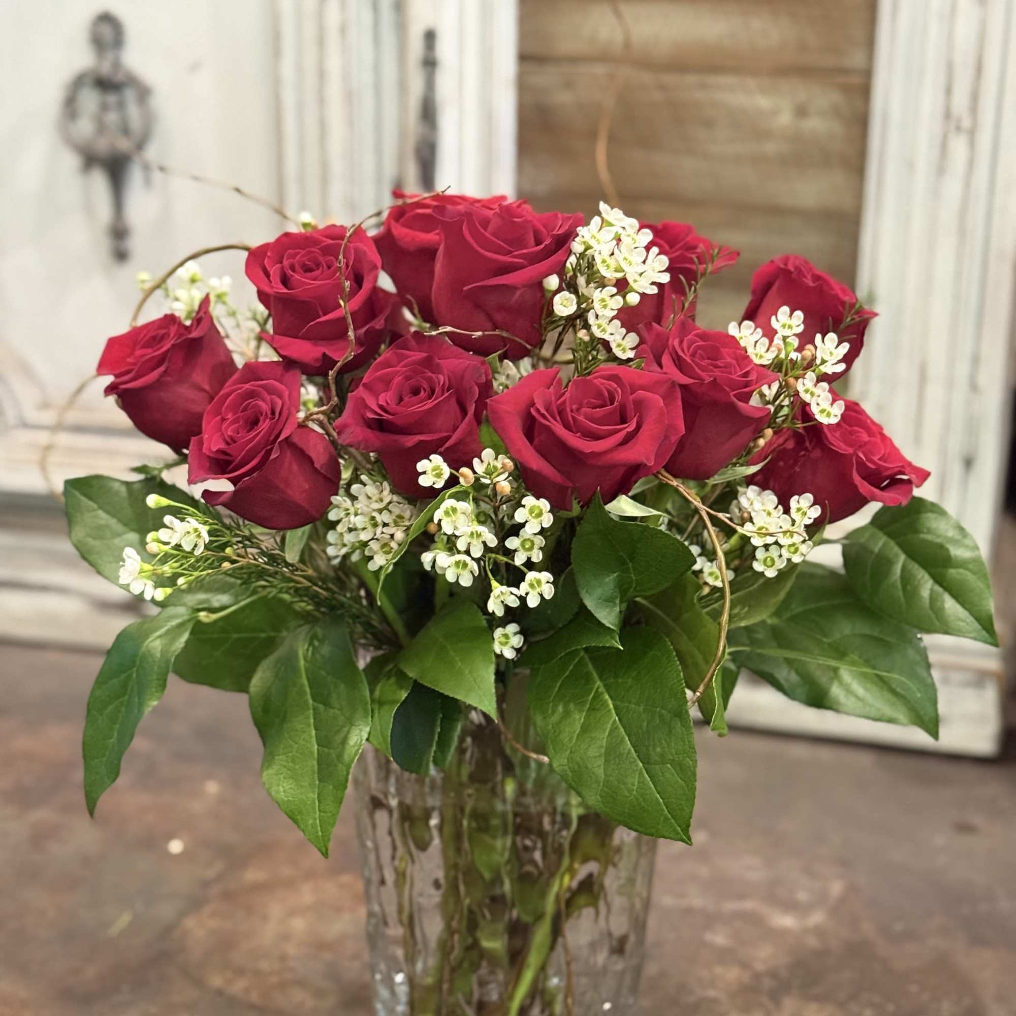 Red roses arranged in a clear glass vase with white filler flowers