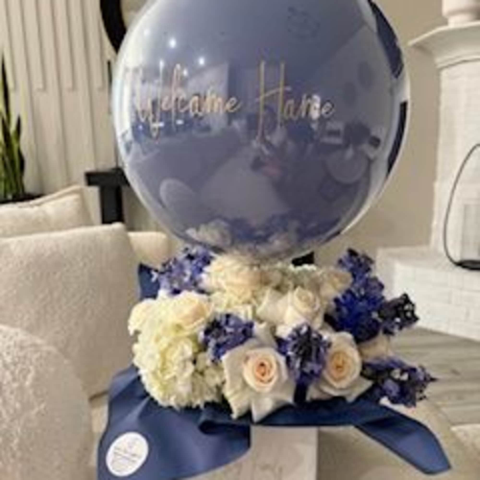 Blue balloon above white and blue roses in a gift arrangement