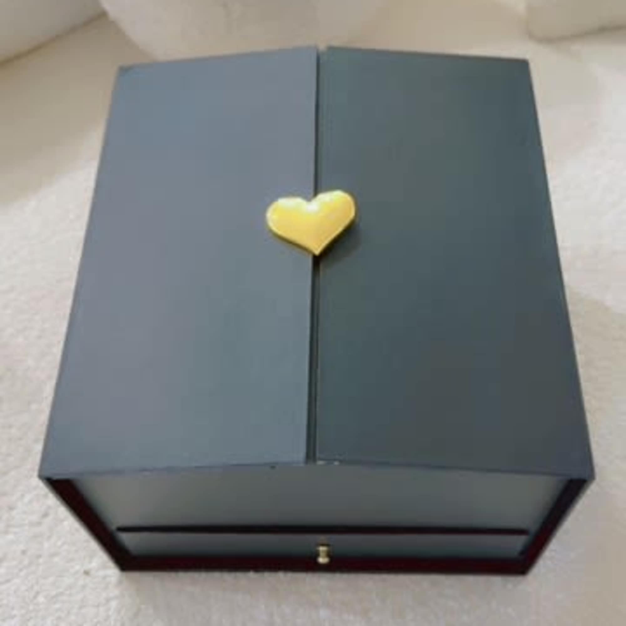 Blue gift box with a gold heart clasp on a white surface