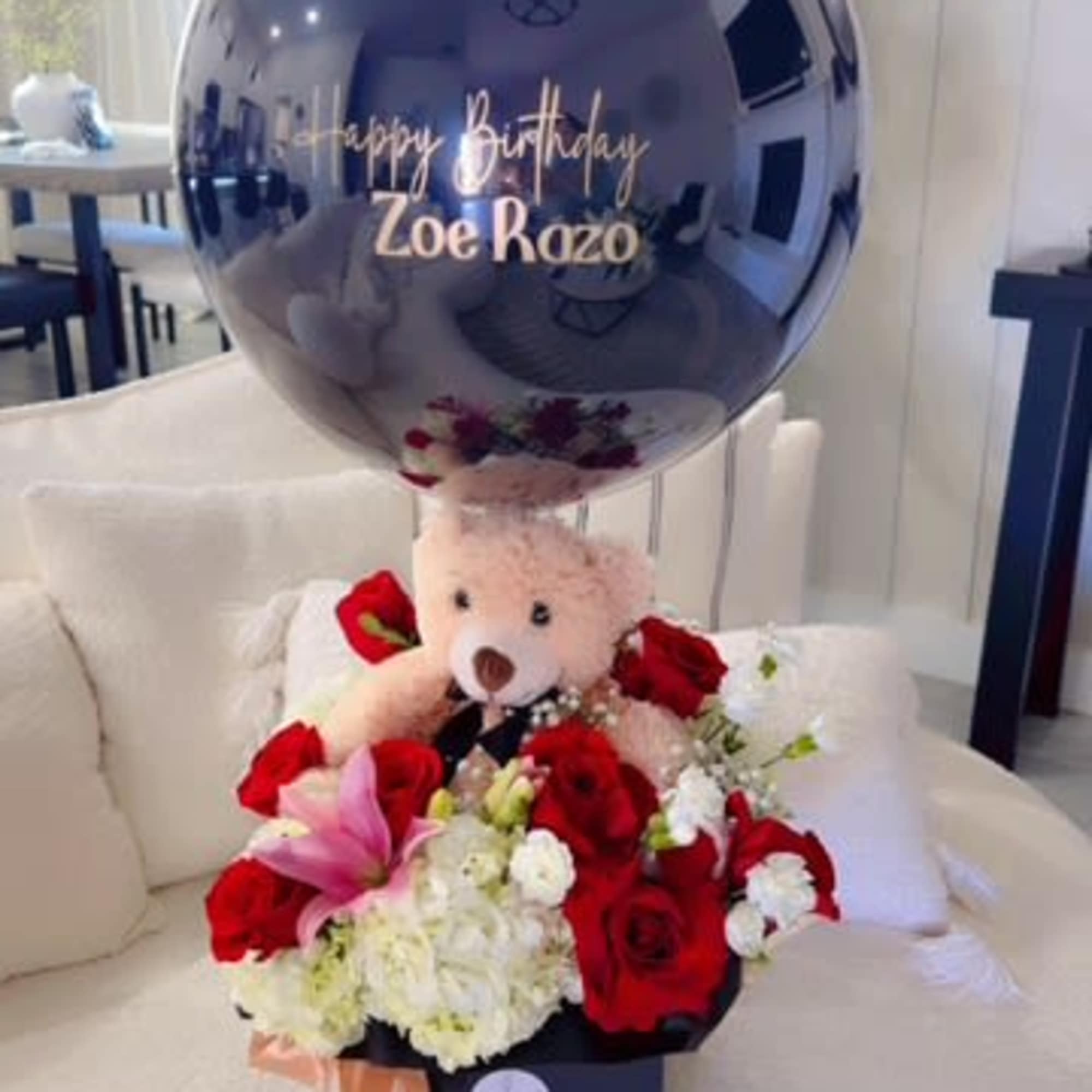 Teddy bear with red and white flowers and a birthday balloon