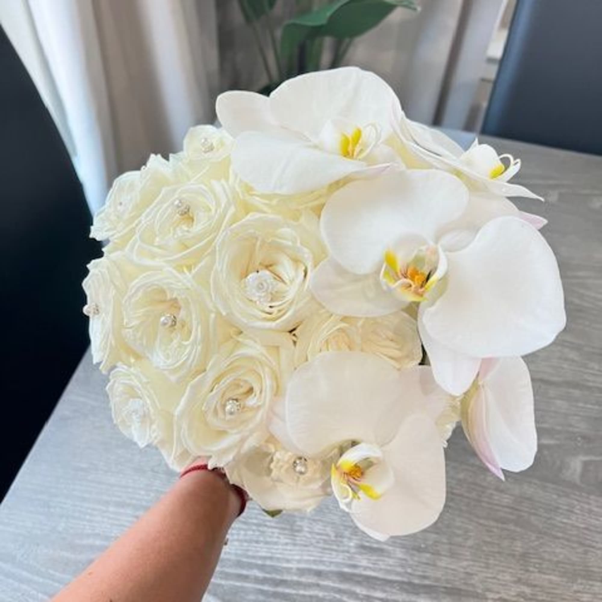 White bouquet of orchids and roses held in hand