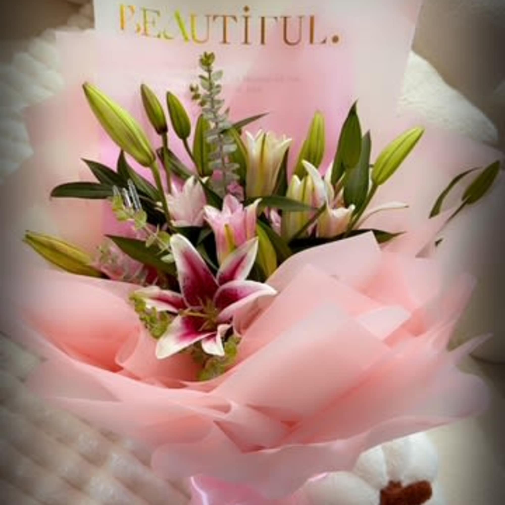 Bouquet of pink and white lilies wrapped in pink paper